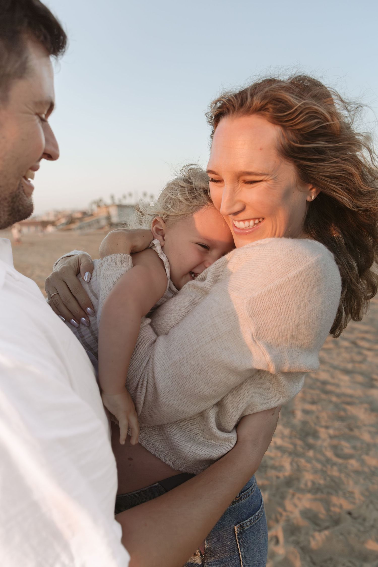Candid moments of joy and laughter captured on a sandy beach during golden hour.