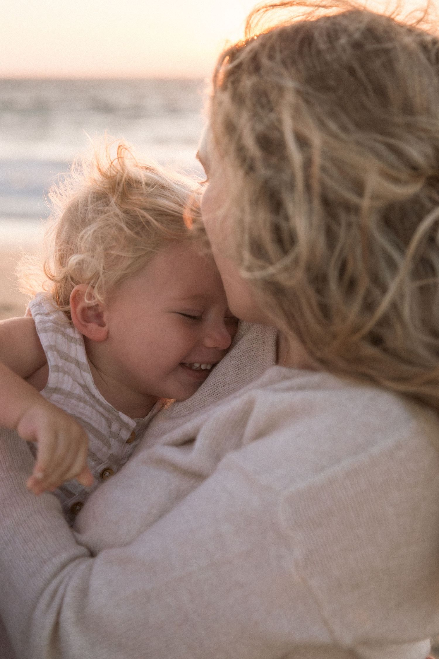 Tender moment between parent and child cuddling together in warm sunset light.