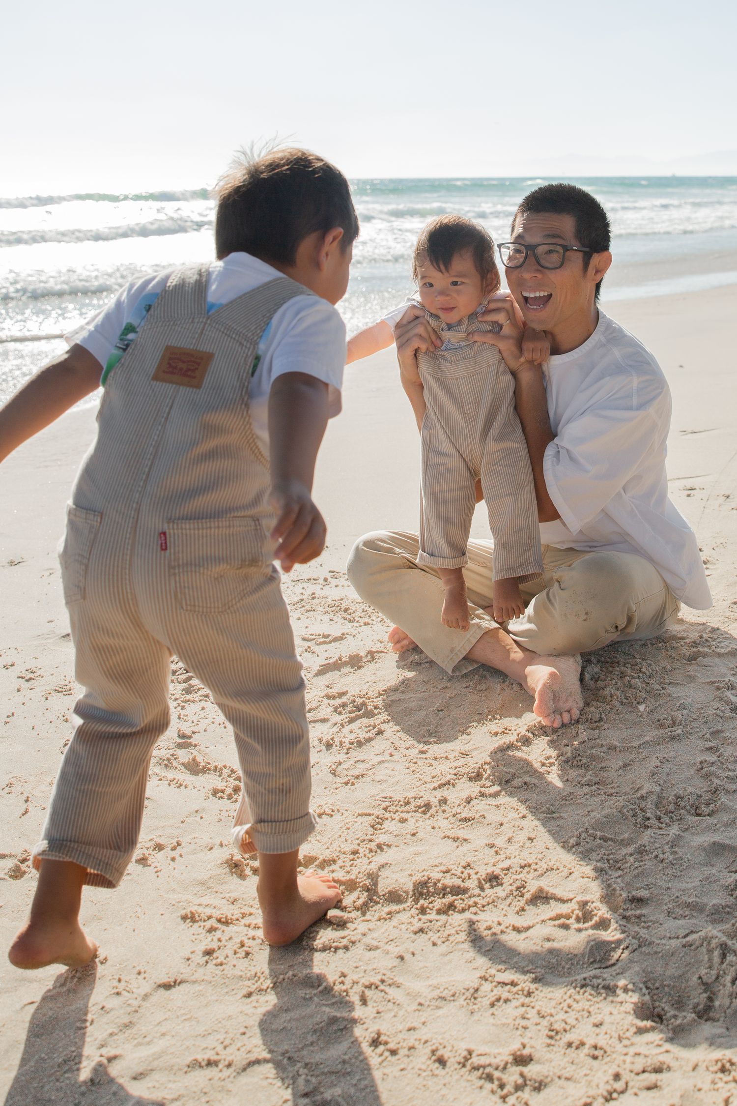 Playful beach photoshoot showing children crawling and playing in the sand.