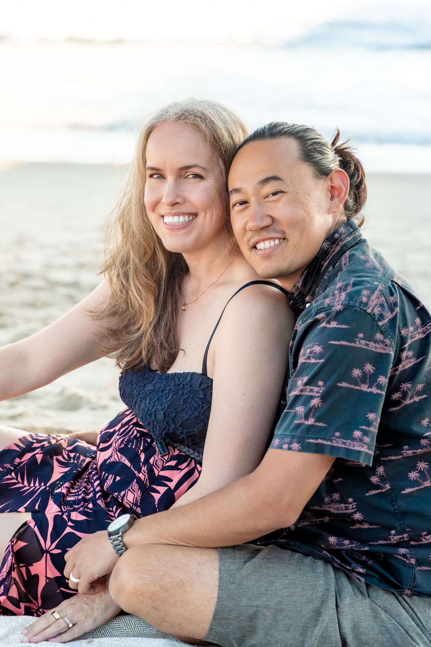 Romantic beach photoshoot featuring a couple in coordinating outfits sharing tender moments.