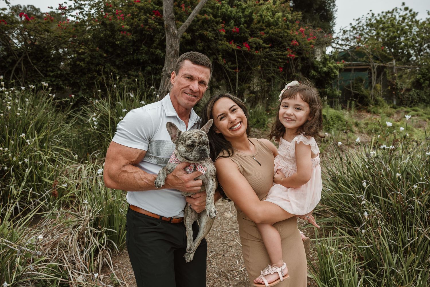 Family photoshoot in natural outdoor setting with greenery.