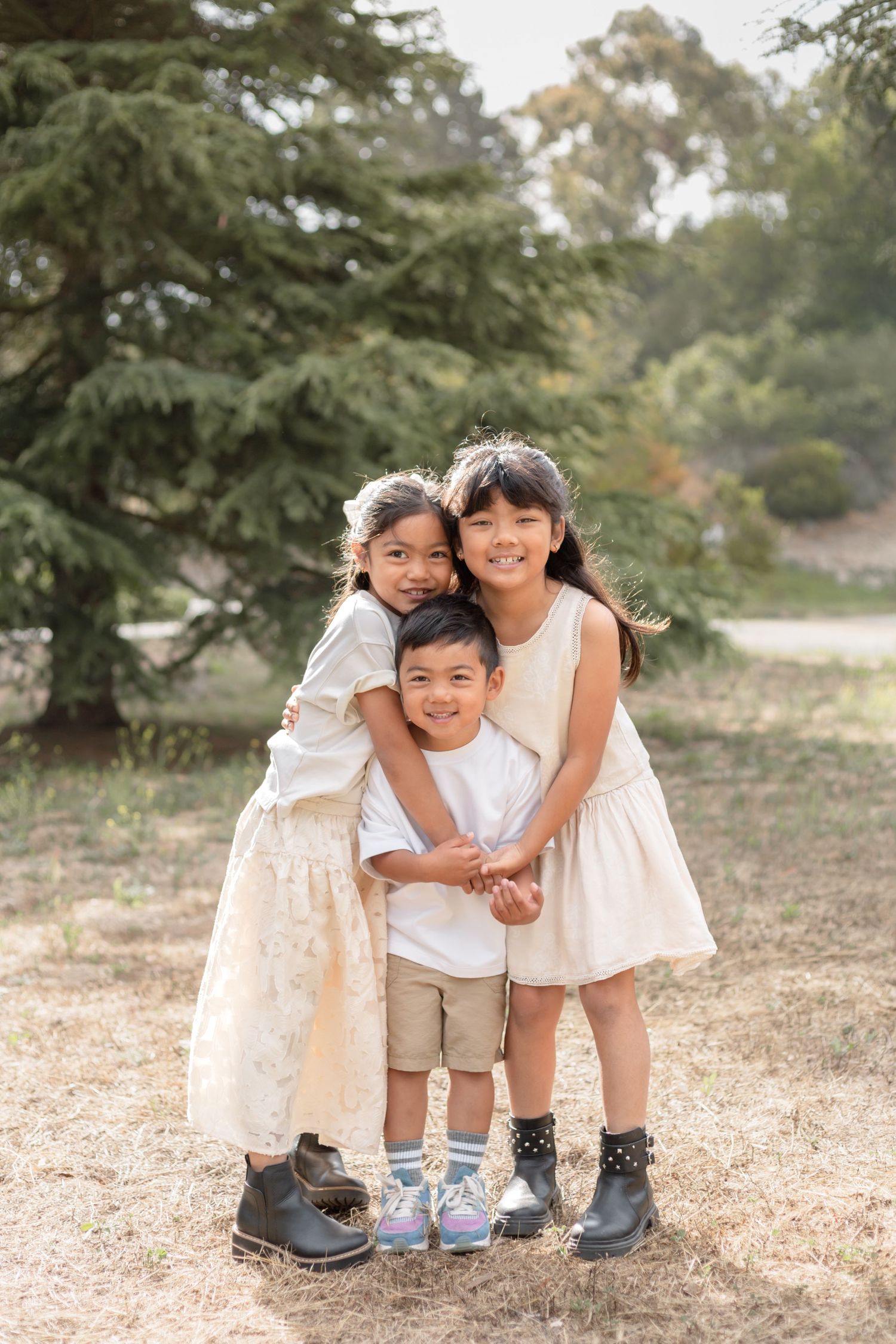 Children in coordinated outfits pose together outdoors for casual family photos.