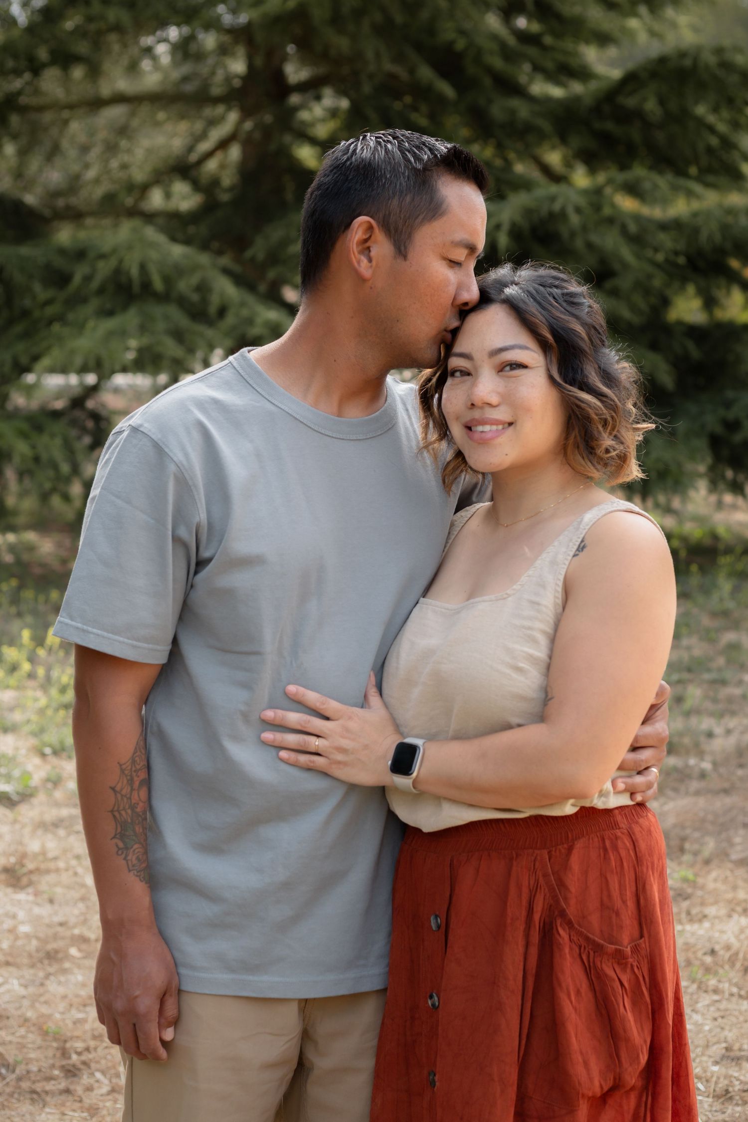 Intimate couple portrait session in casual attire against natural outdoor backdrop.