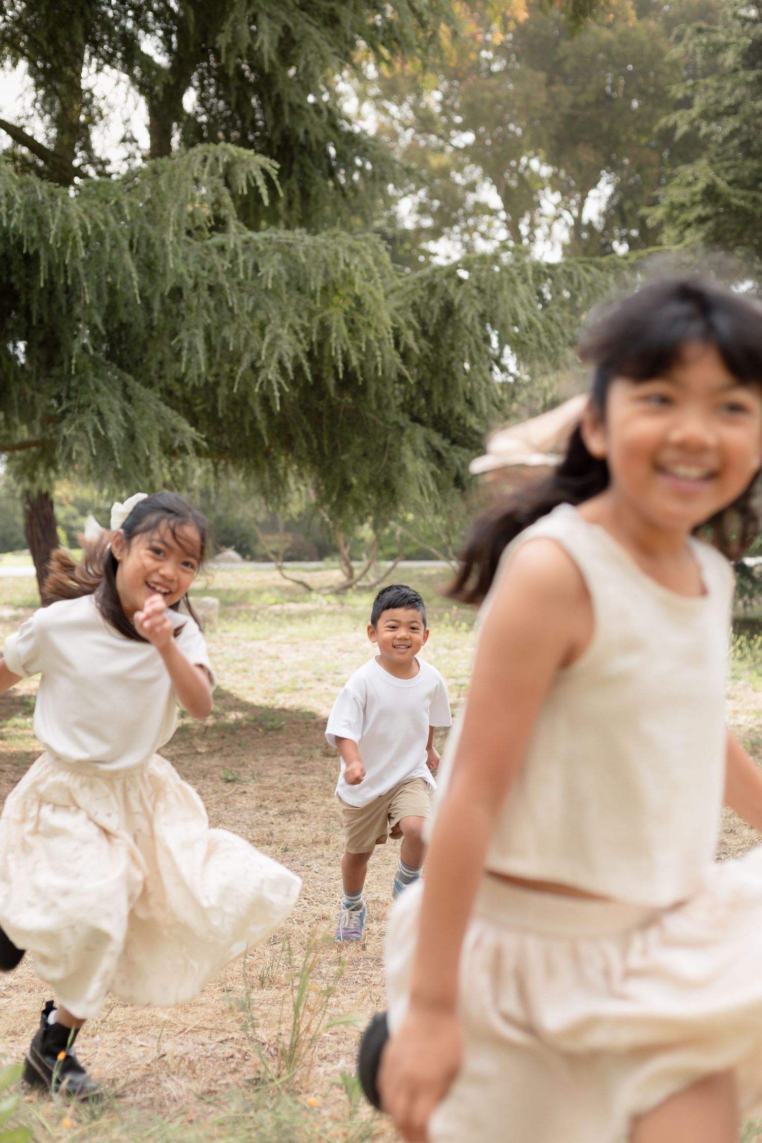 Candid action shots of children running and playing in wooded outdoor area.