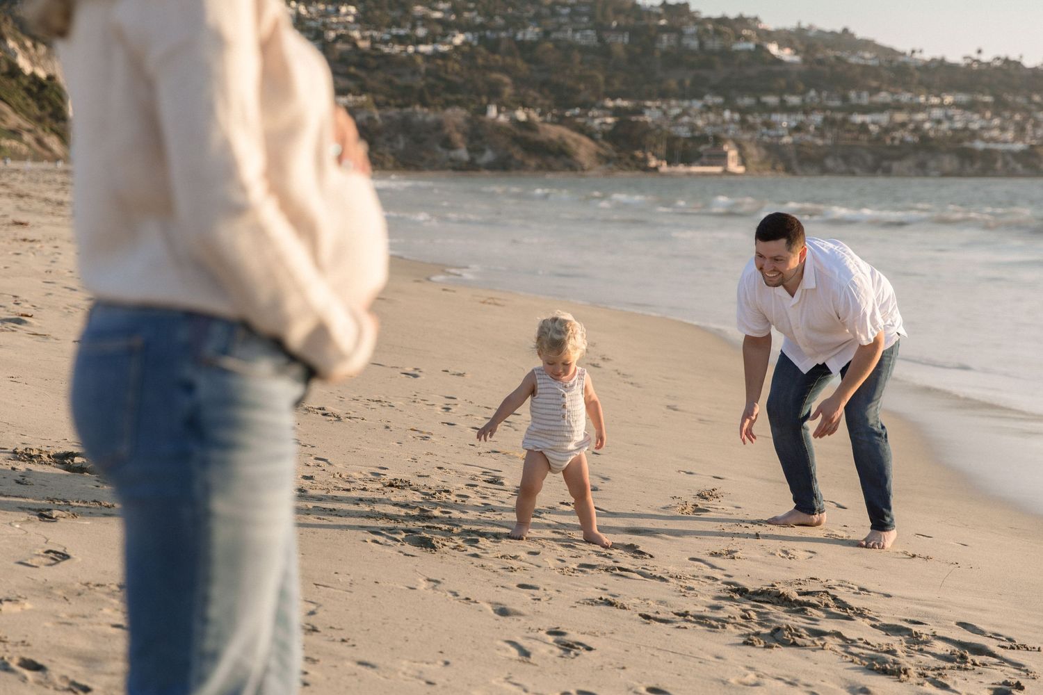 Family enjoying playful moments together on a scenic beach during sunset.