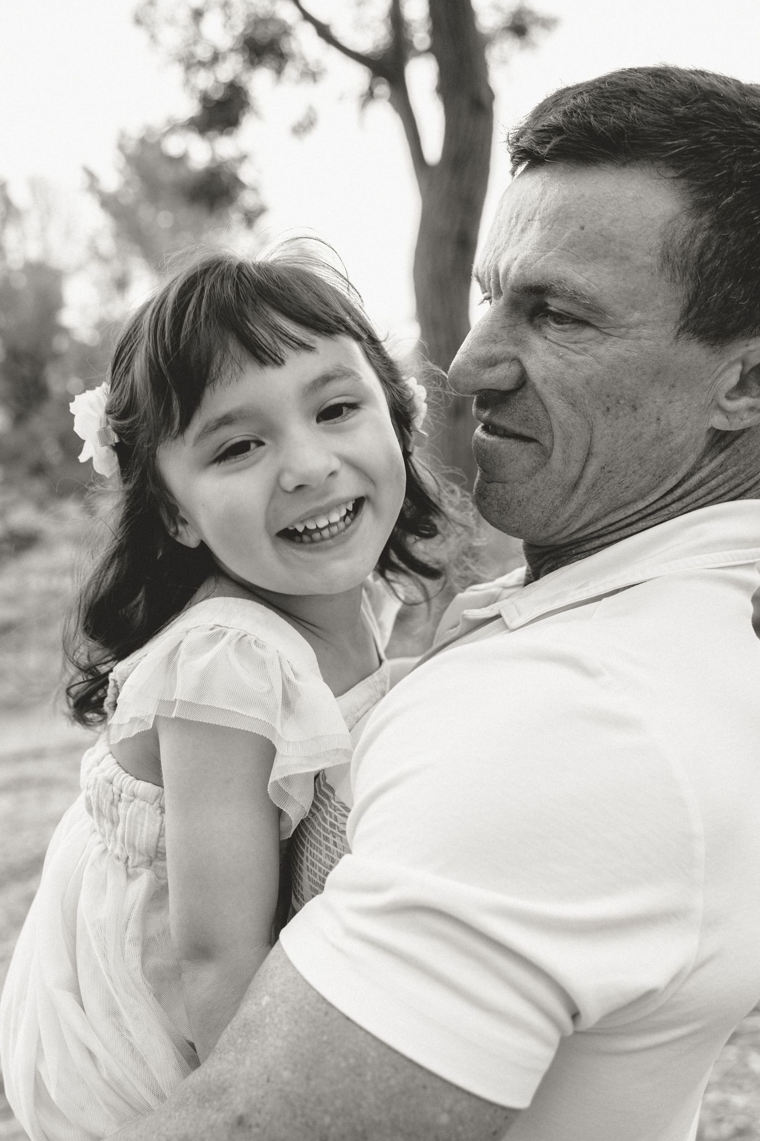 Candid black and white moment of joyful laughter and embrace outdoors.