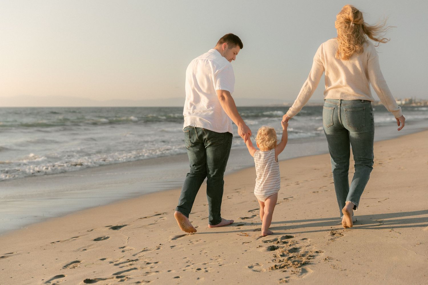 Family running and playing together on beach at sunset creating joyful moments.