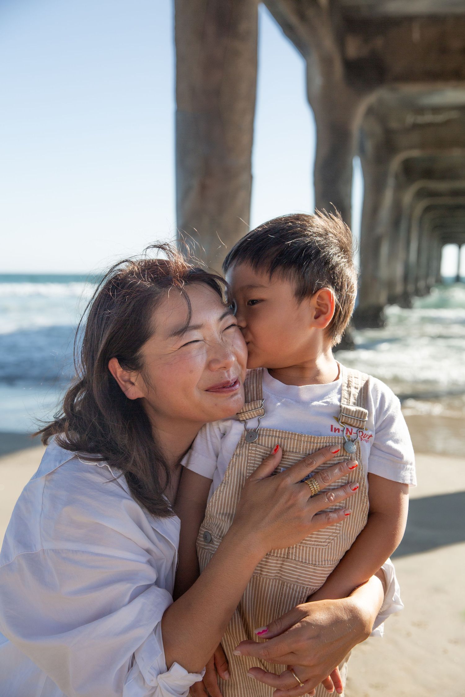 Sweet moments shared between parent and child under a pier at the beach.