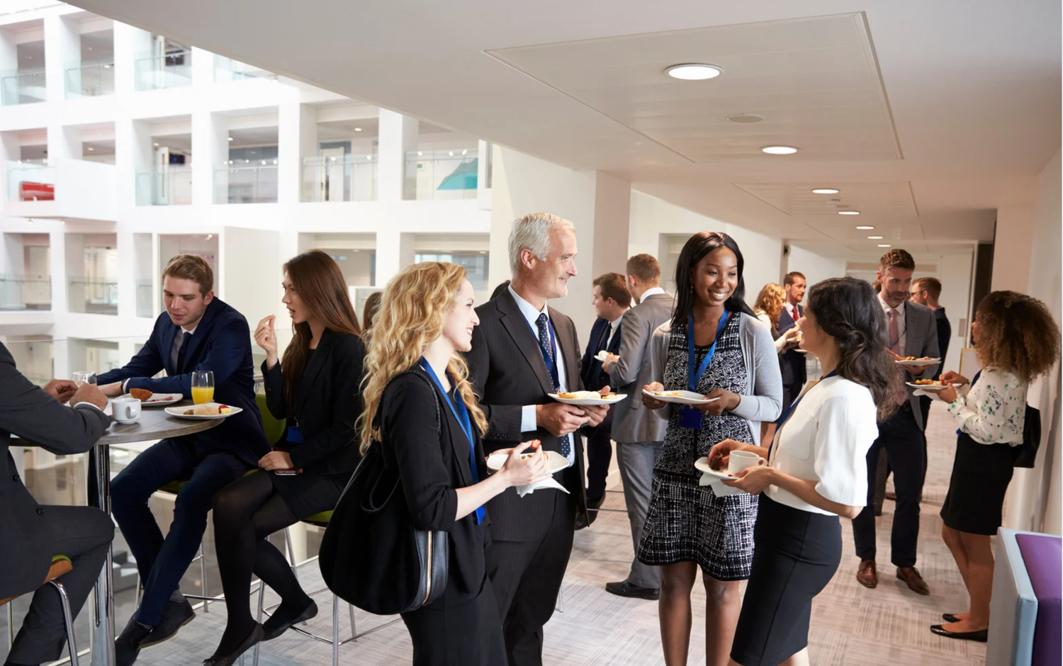 Business professionals networking and socializing during a conference lunch break in modern venue.