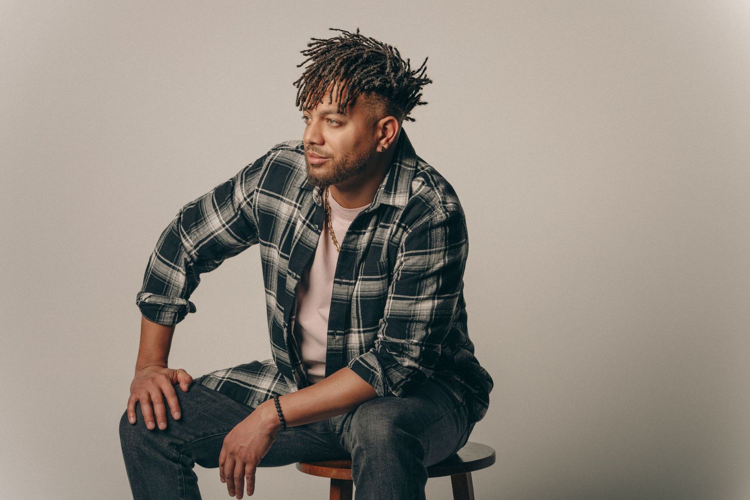 Person in plaid shirt poses casually during professional studio photoshoot.
