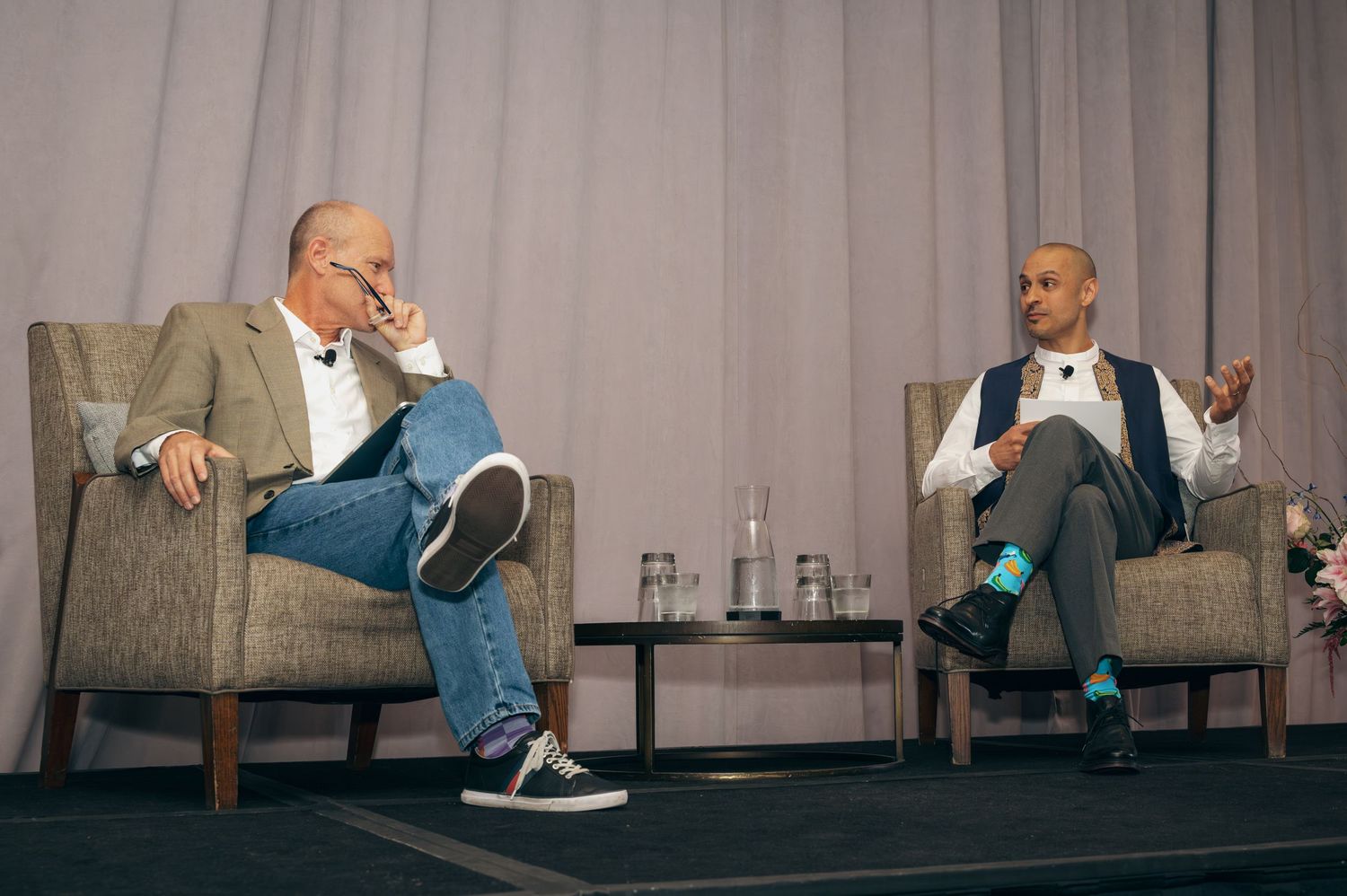 Two speakers engaged in conversation on stage at a business conference.