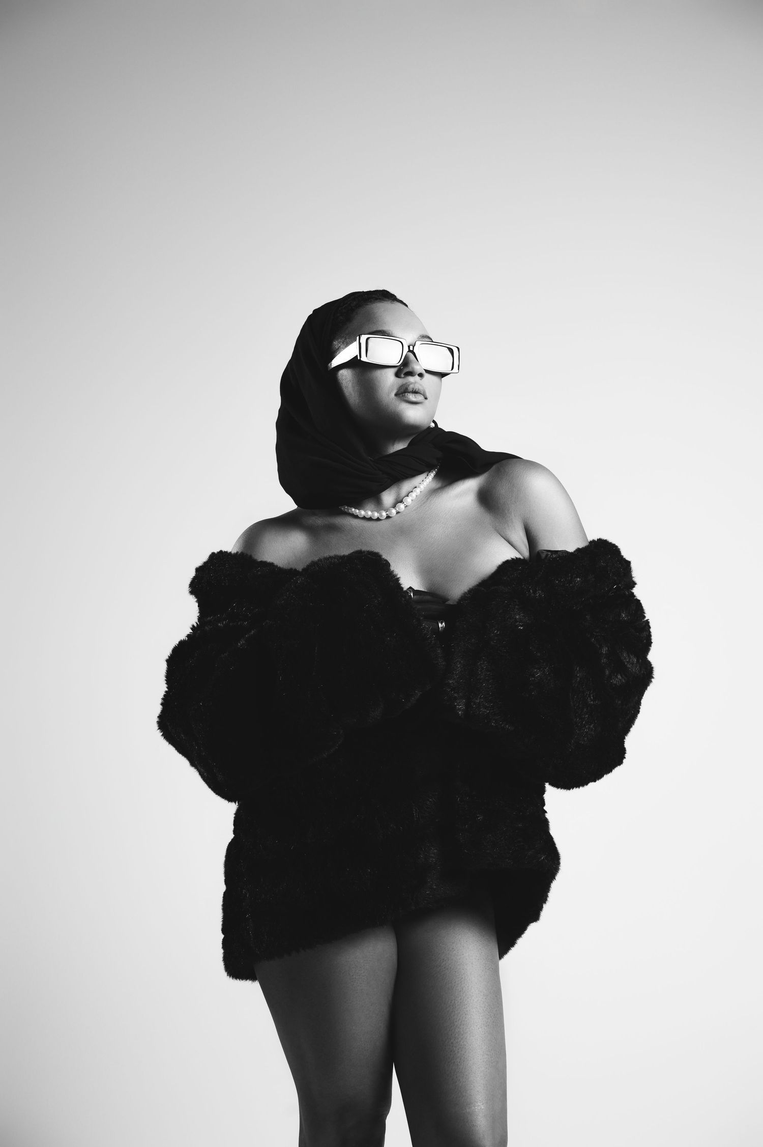 Black and white artistic fashion photo series showing dramatic poses in dark ruffled clothing against light background.