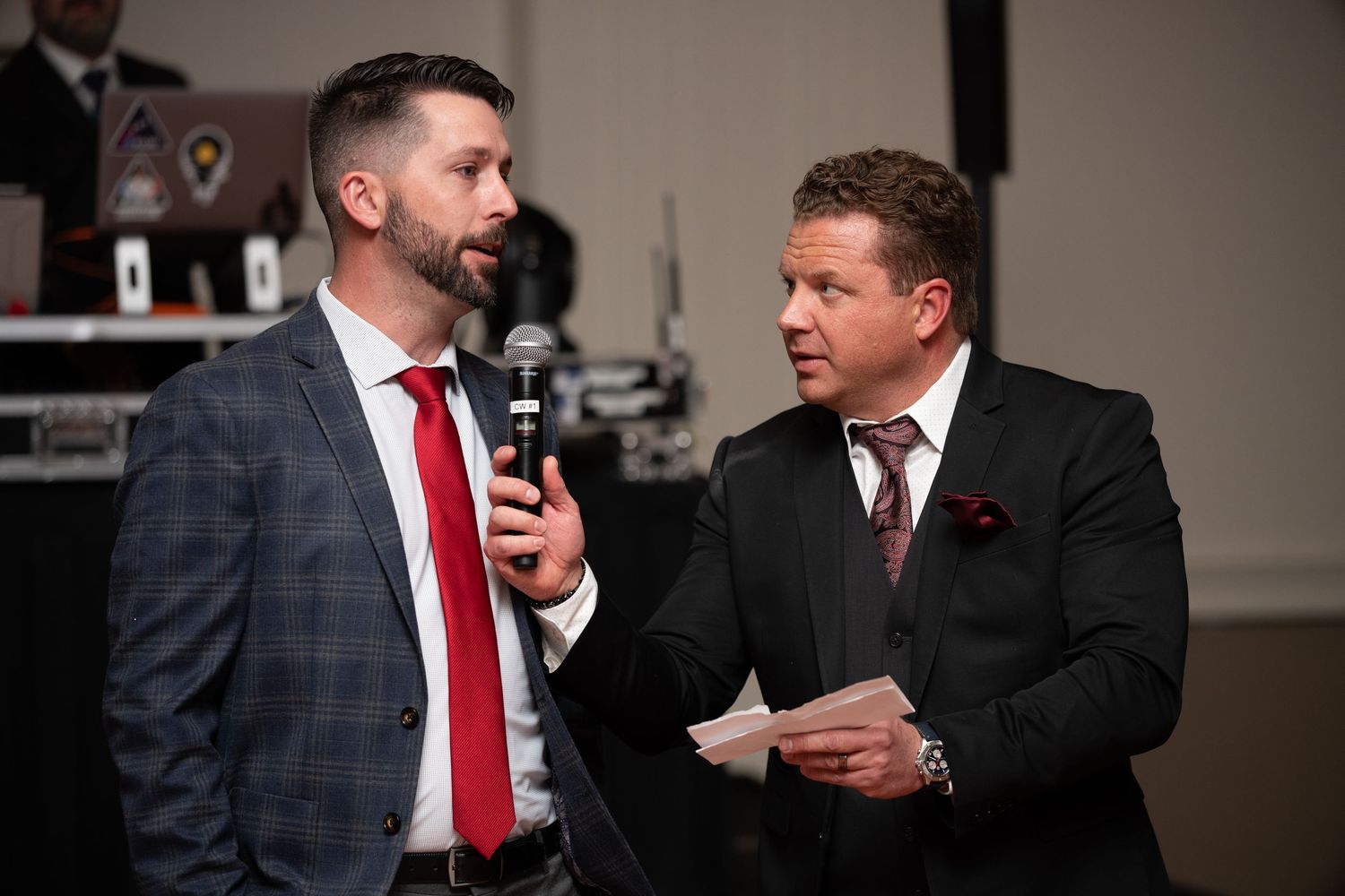 Business professionals in suits engaged in animated conversation at formal event.