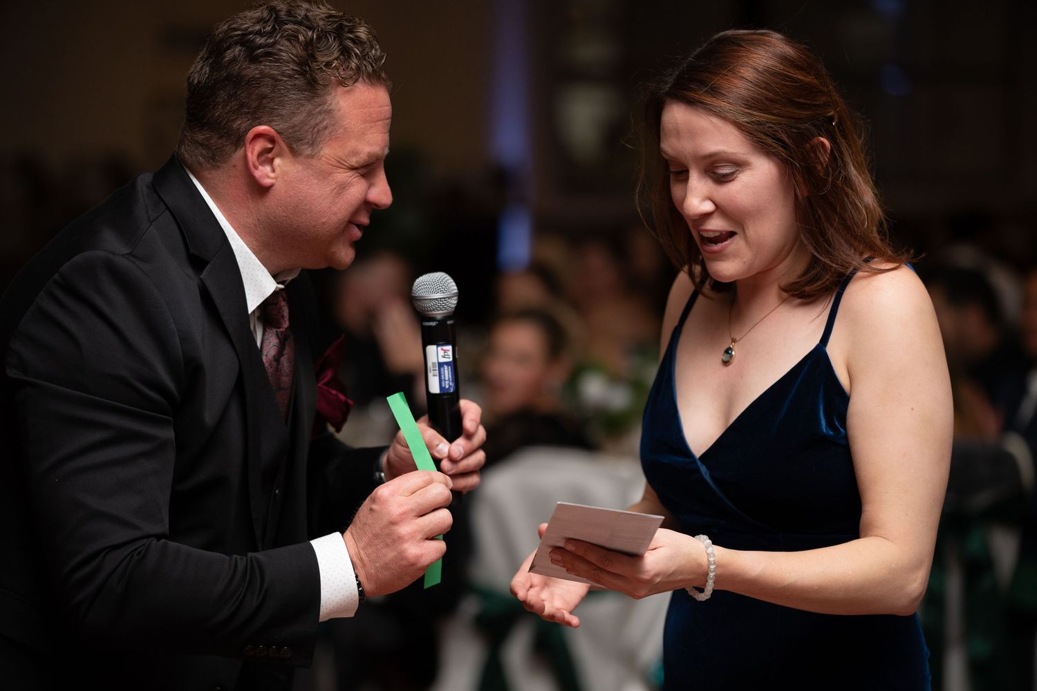 Couple in formal attire playing a party game with glowing sticks at an event.
