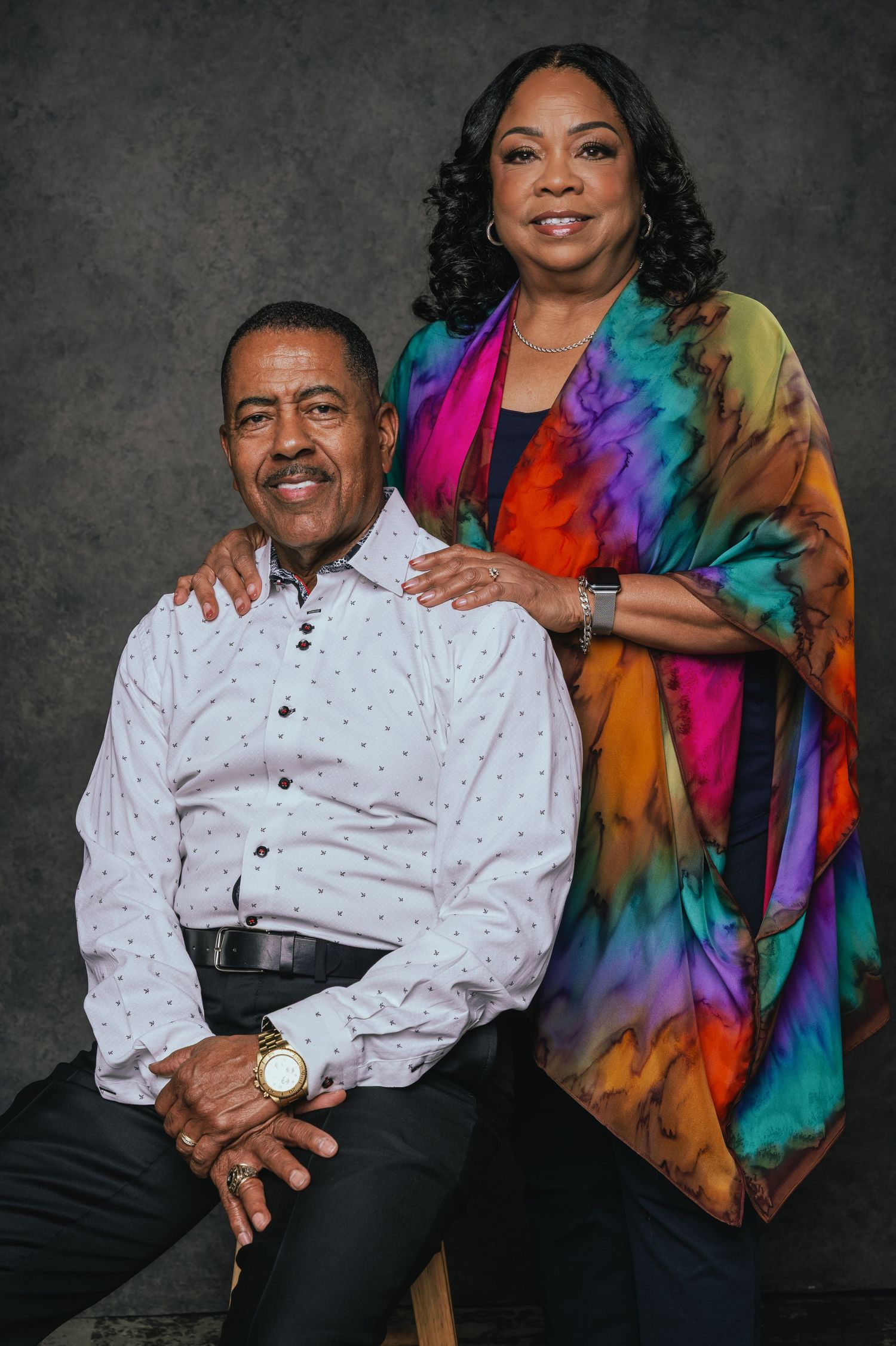 Studio portrait of two people wearing colorful tie-dye scarf and polka dot shirt.