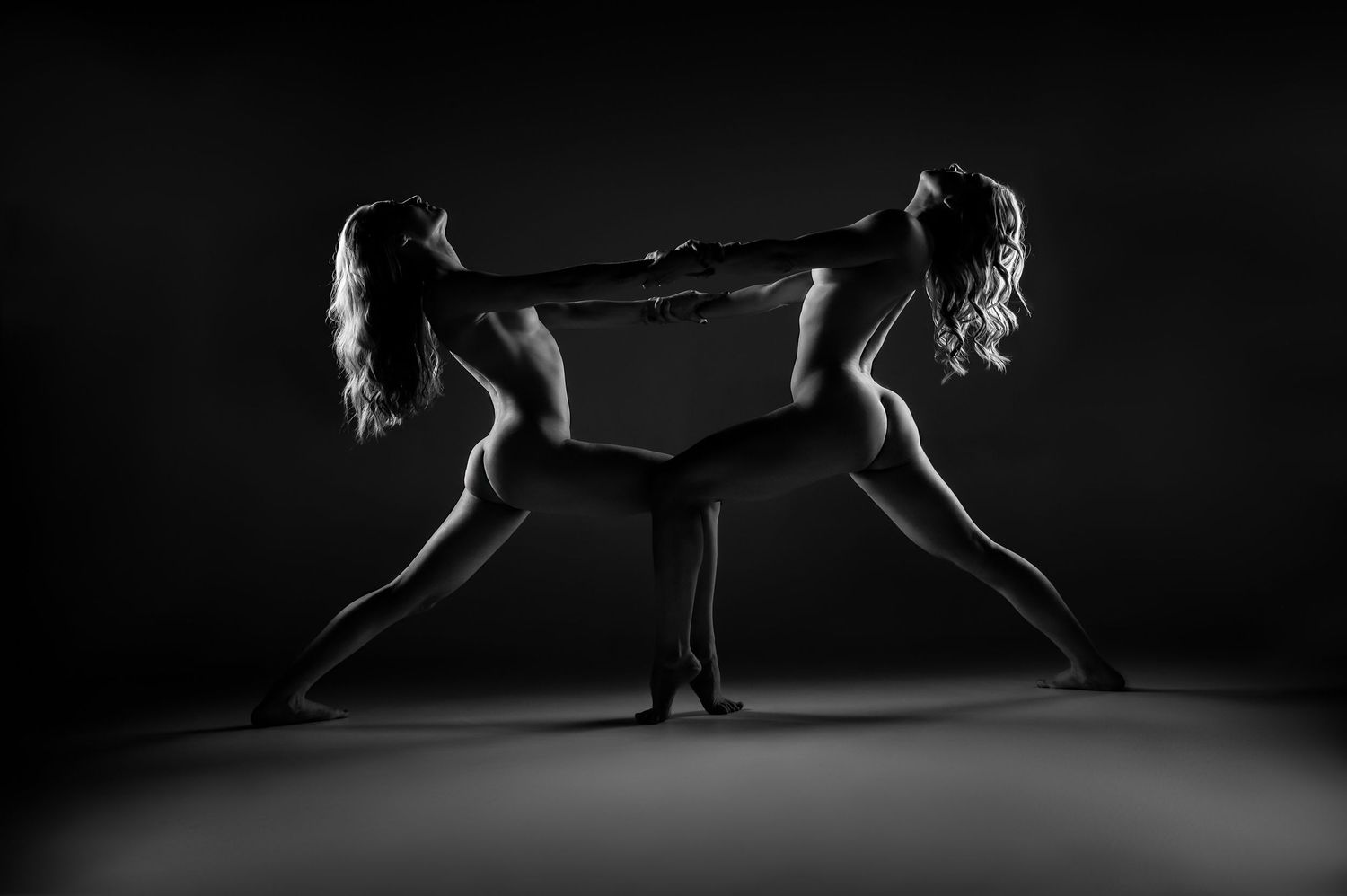 Two women in artistic black and white fine art photography, posed symmetrically in a dynamic dance pose.