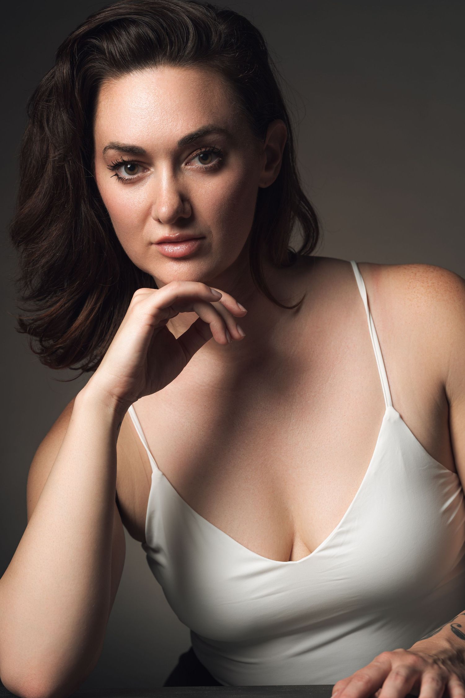 Dramatic studio portraits in white camisole with moody lighting and thoughtful poses.