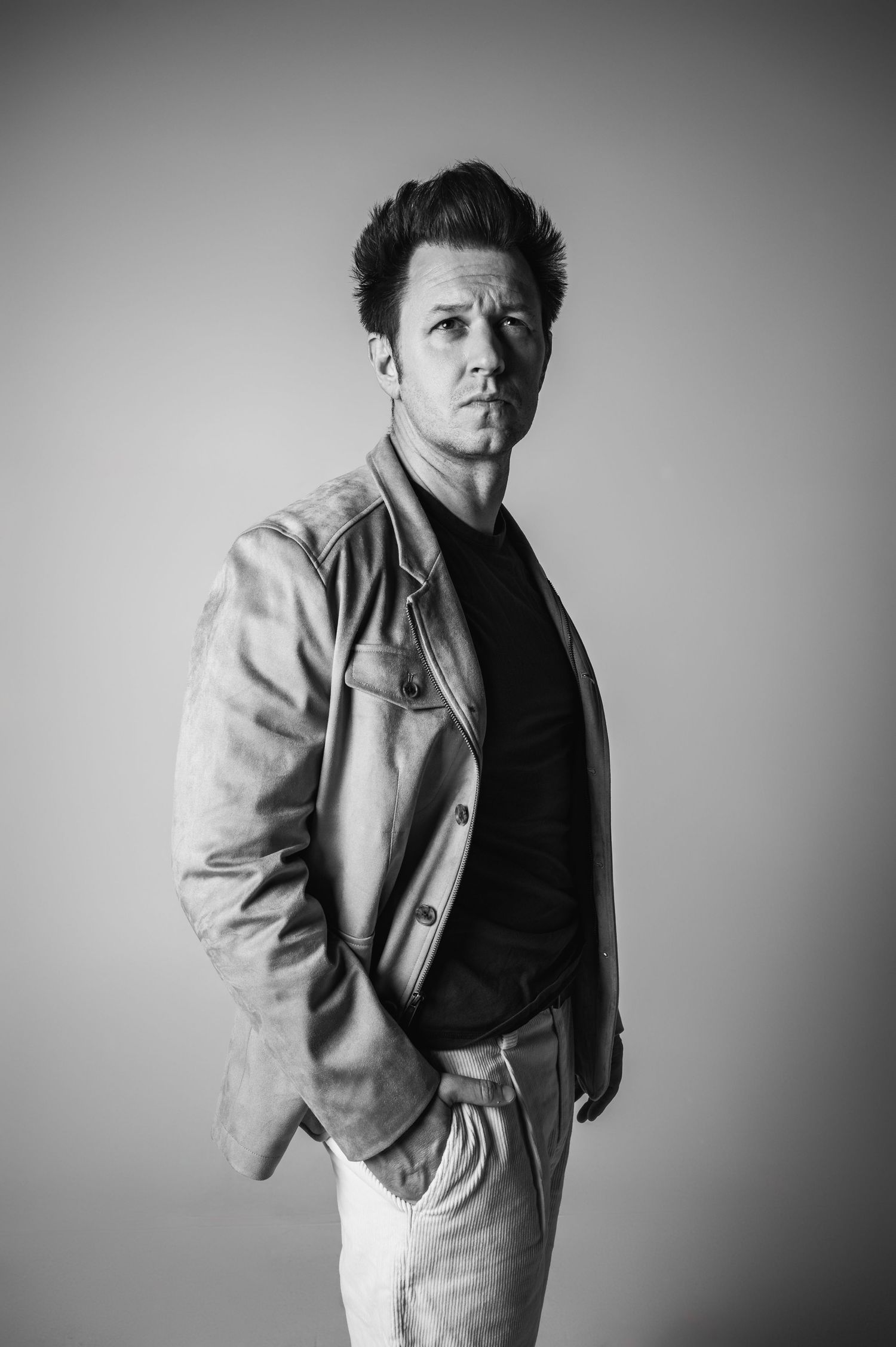 Black and white portrait series showing dramatic poses in light colored jacket.