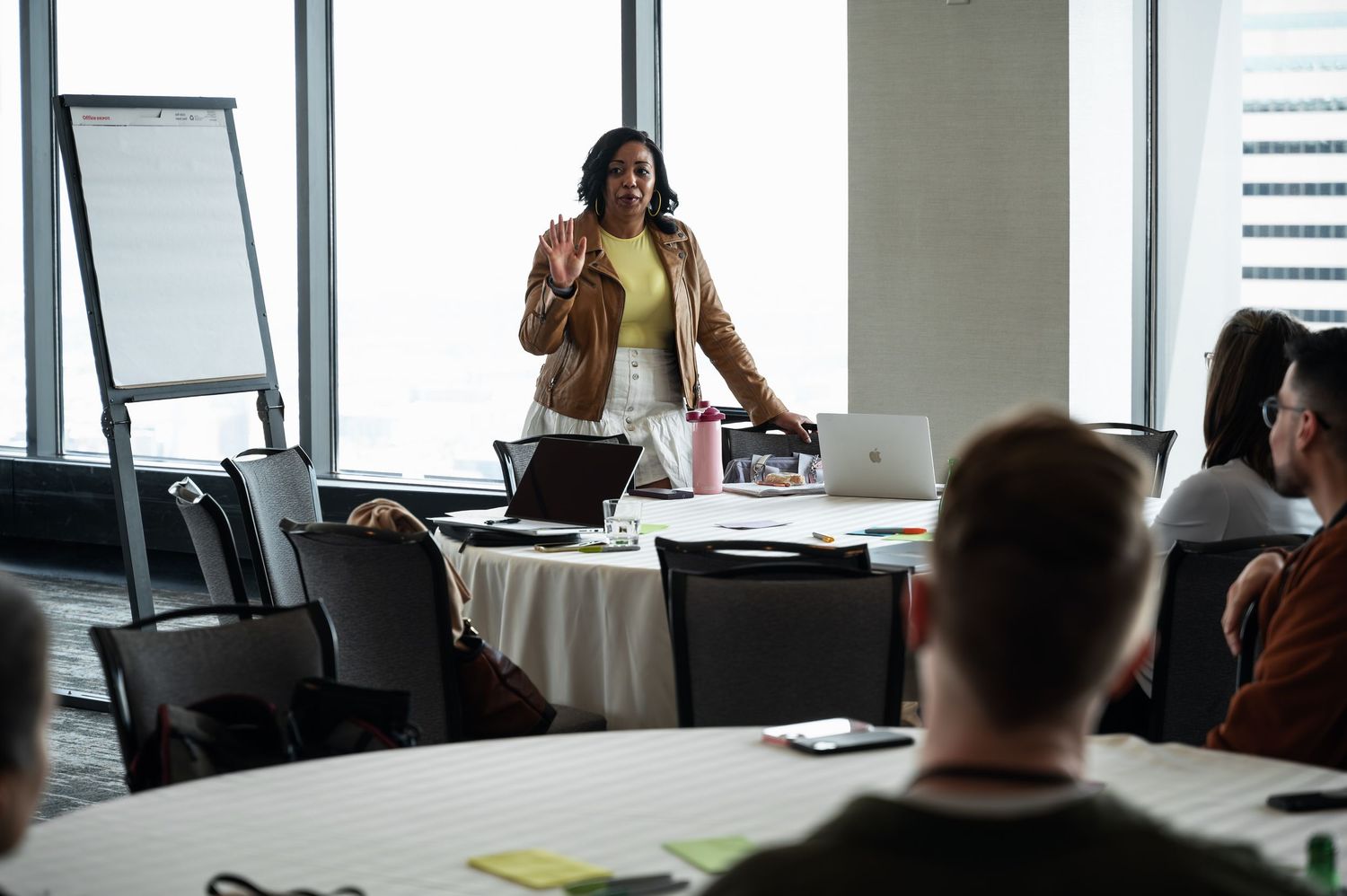 Business professionals gather around a modern conference room table for a meeting in a bright office space.