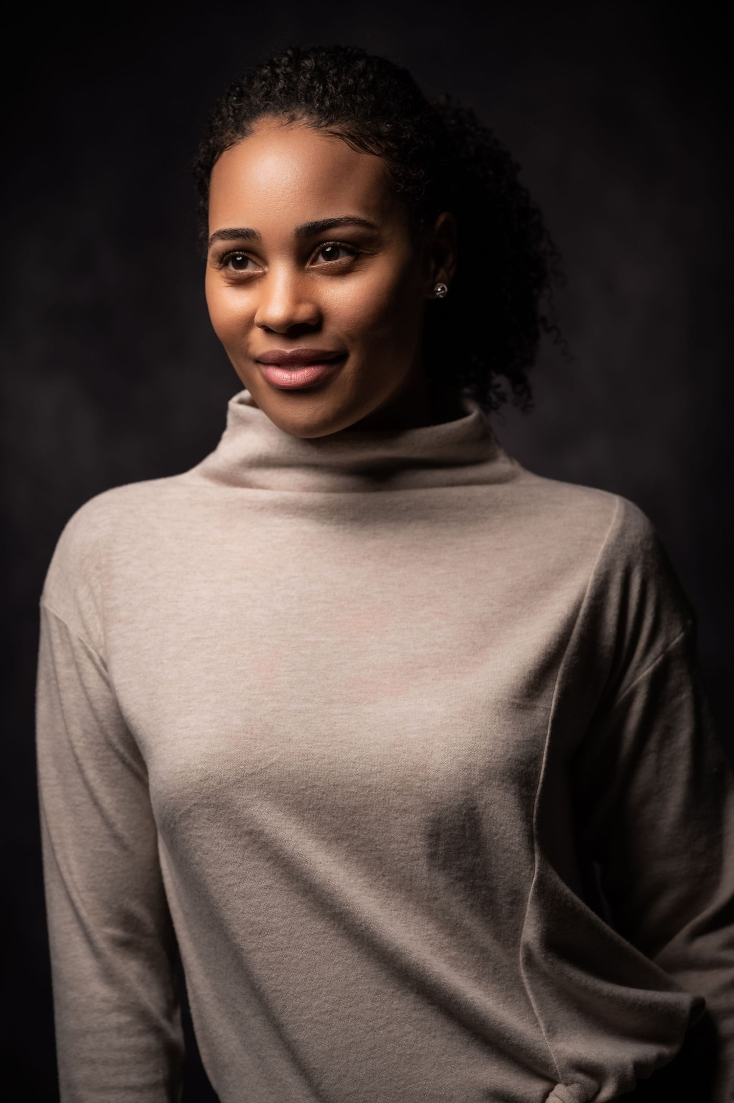 Portrait series showing warm expressions against dark background wearing beige turtleneck sweater.