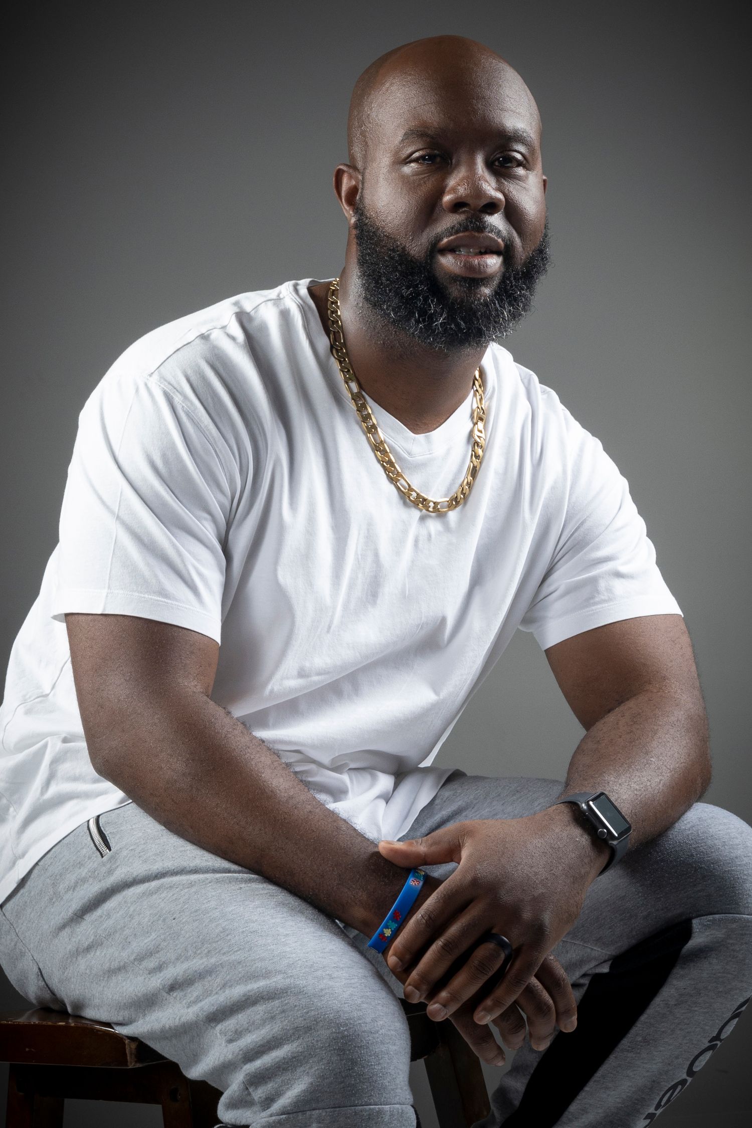 A series of portraits showing someone wearing a white t-shirt and gray pants sitting casually against a gray backdrop.