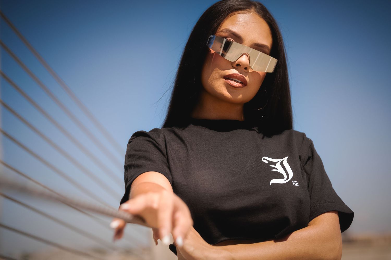 A person in a black t-shirt sits outdoors against a blue sky background with diagonal lines visible.
