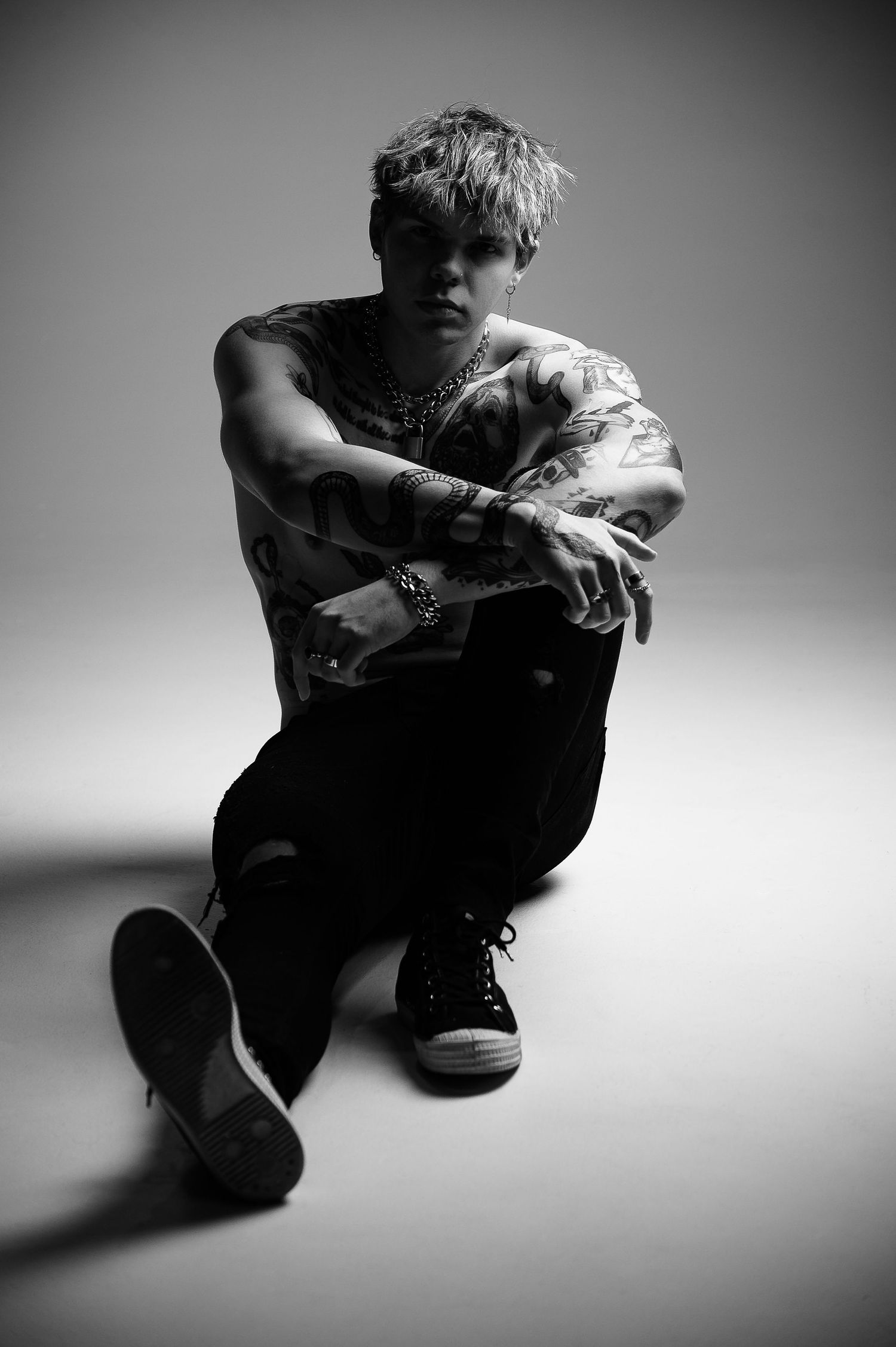 Black and white artistic portrait series showing person in crouched positions against minimalist backdrop.