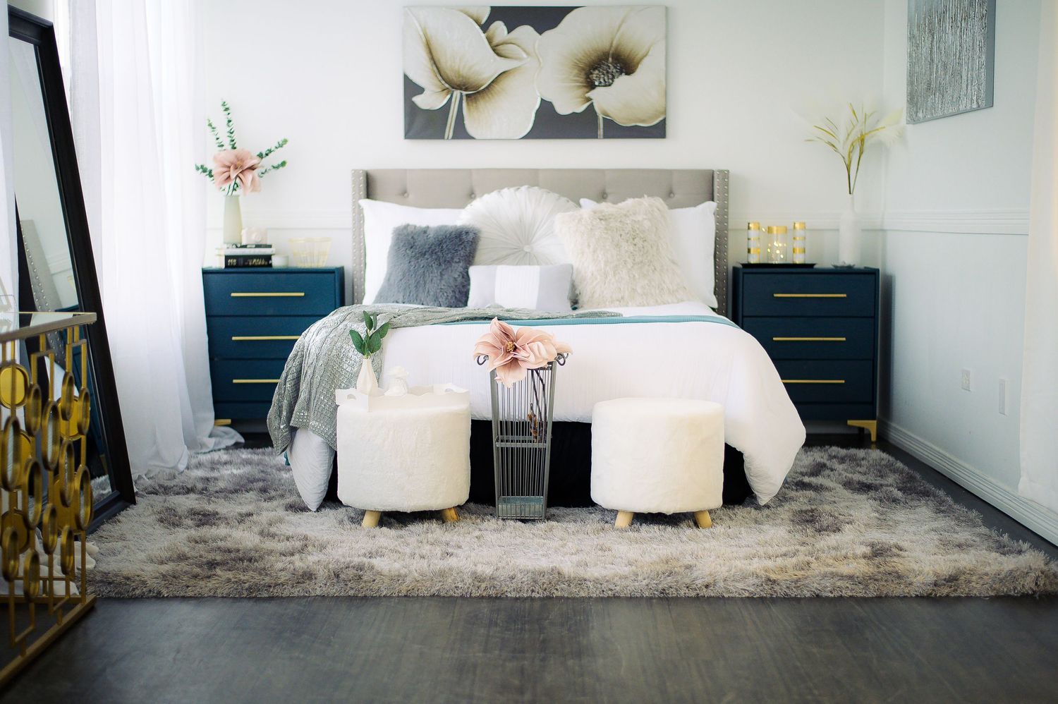 A modern living room features a plush gray area rug, white seating, and contemporary decor with metallic accents.