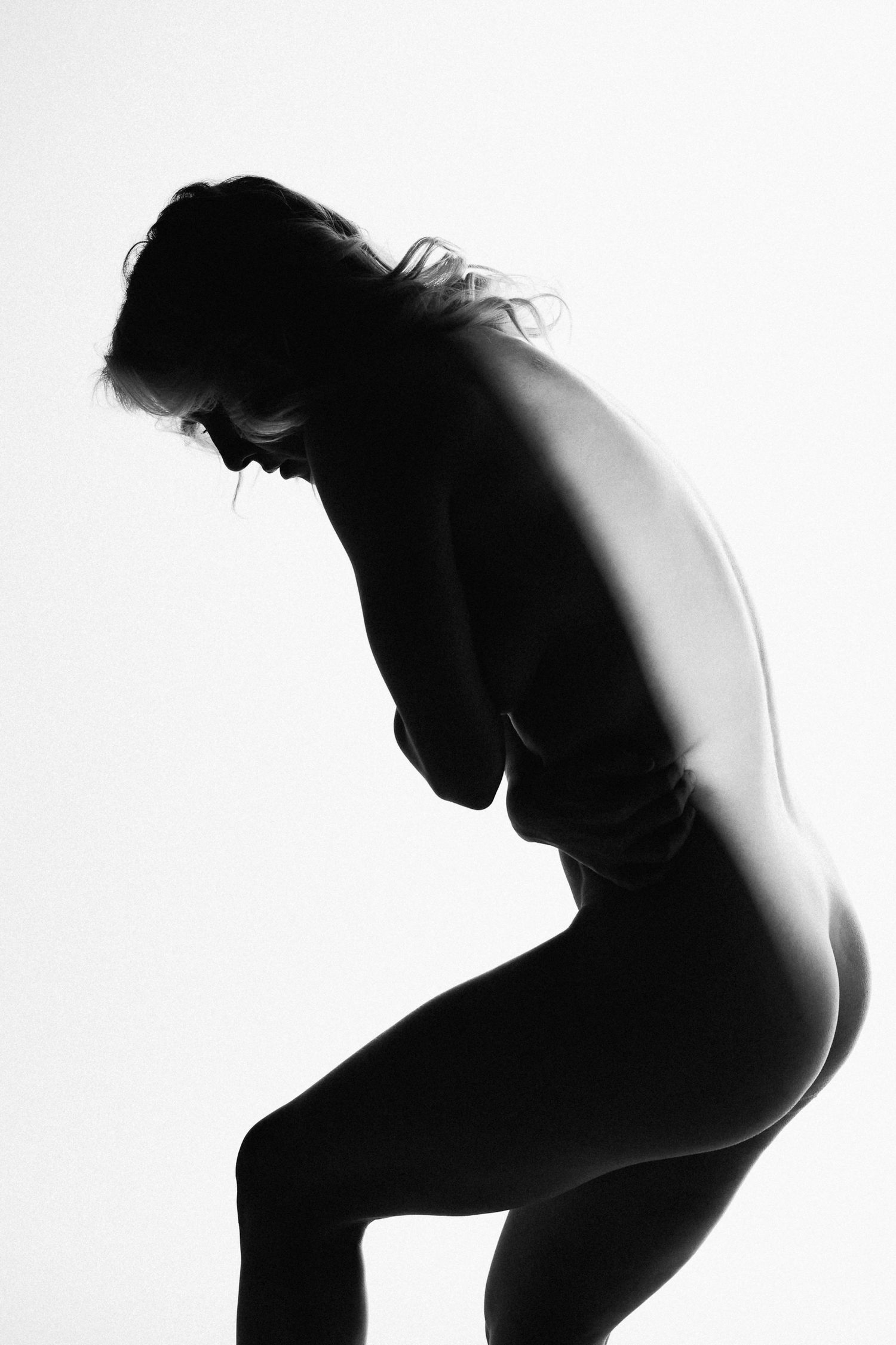 Black and white silhouette of a woman in a graceful pose against a white background.