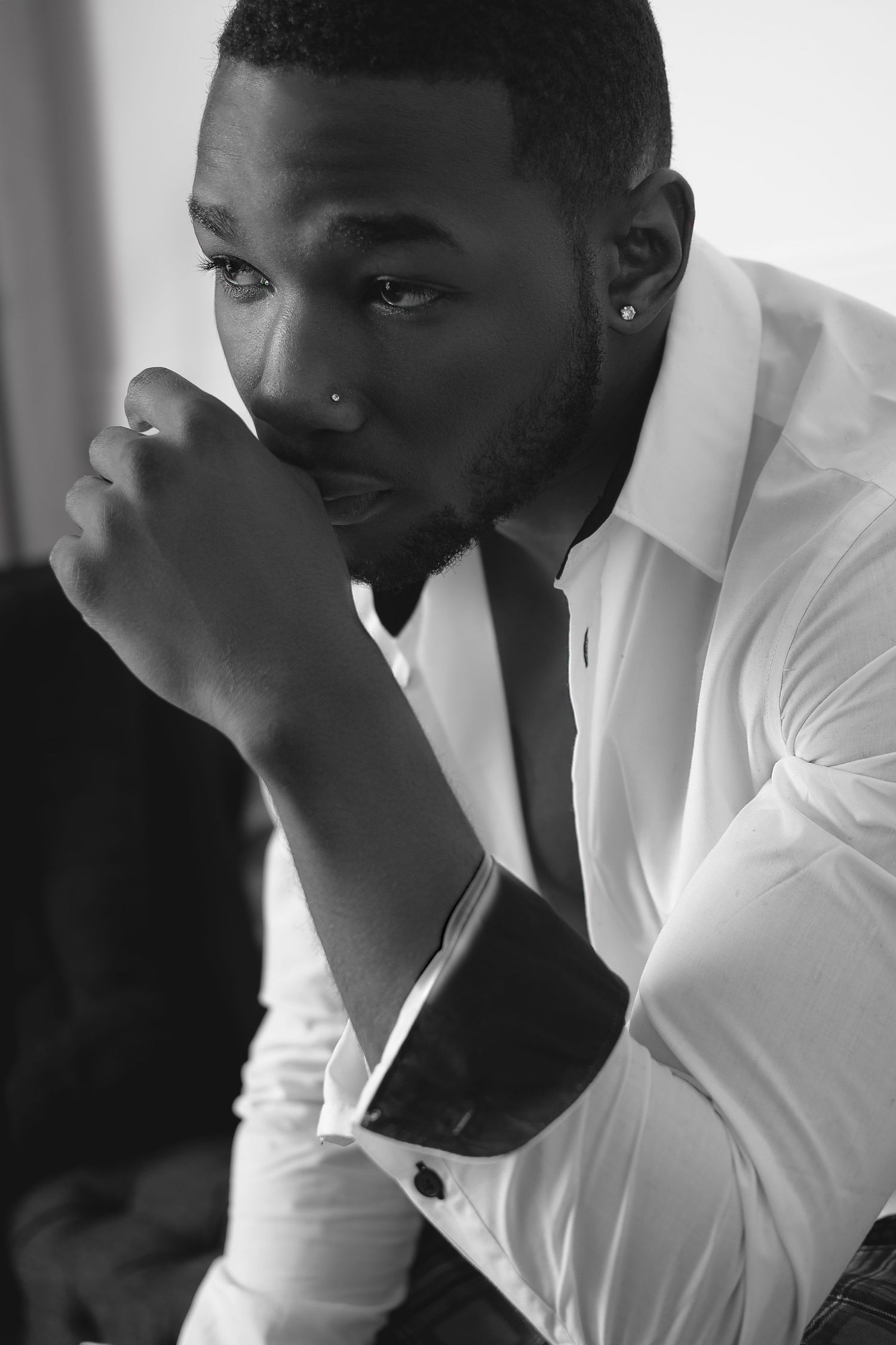 A series of black and white photos showing someone in a white shirt resting their hand thoughtfully on their face.