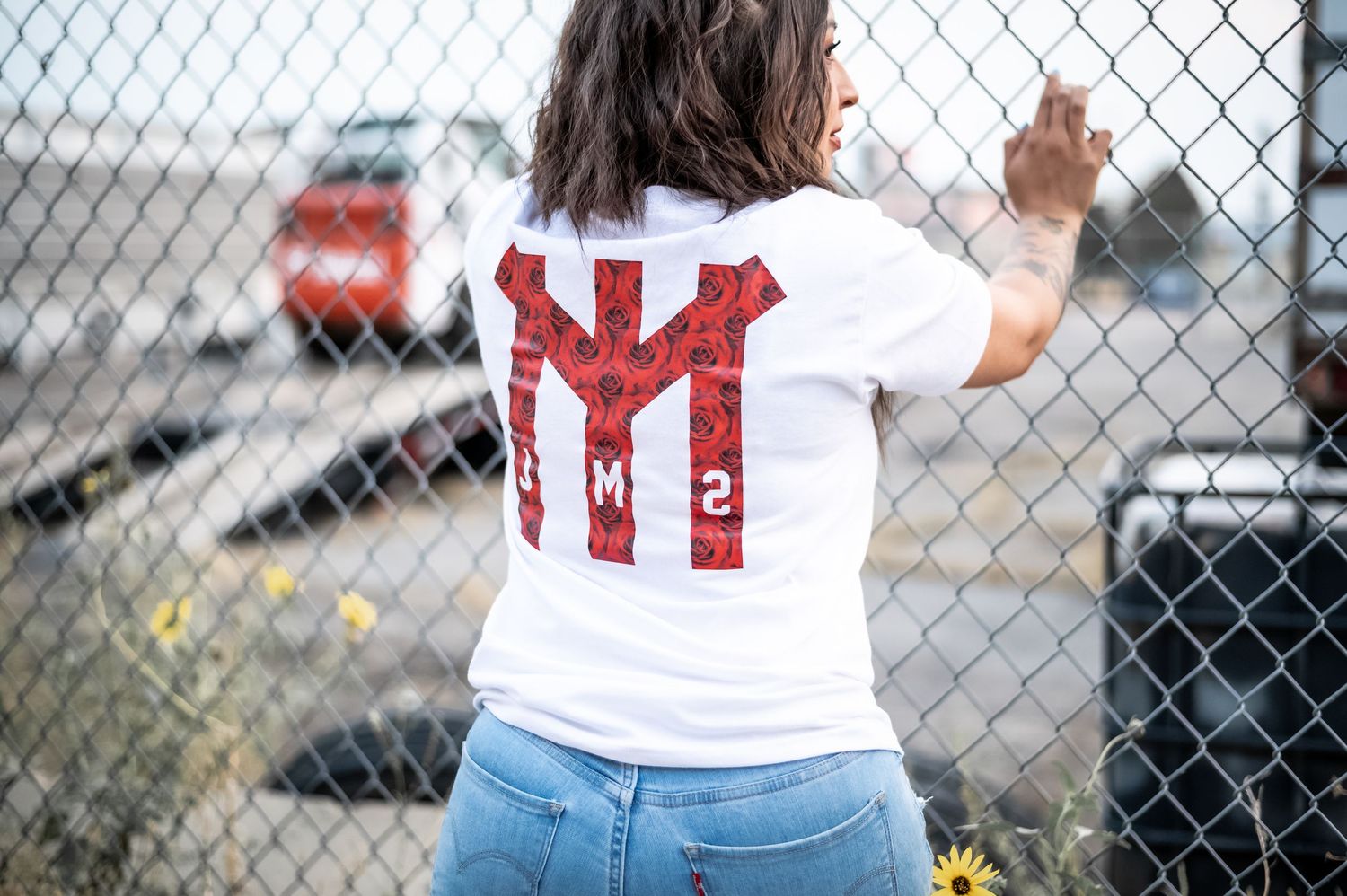 A chain link fence with multiple people standing behind it in casual clothing and sports attire.