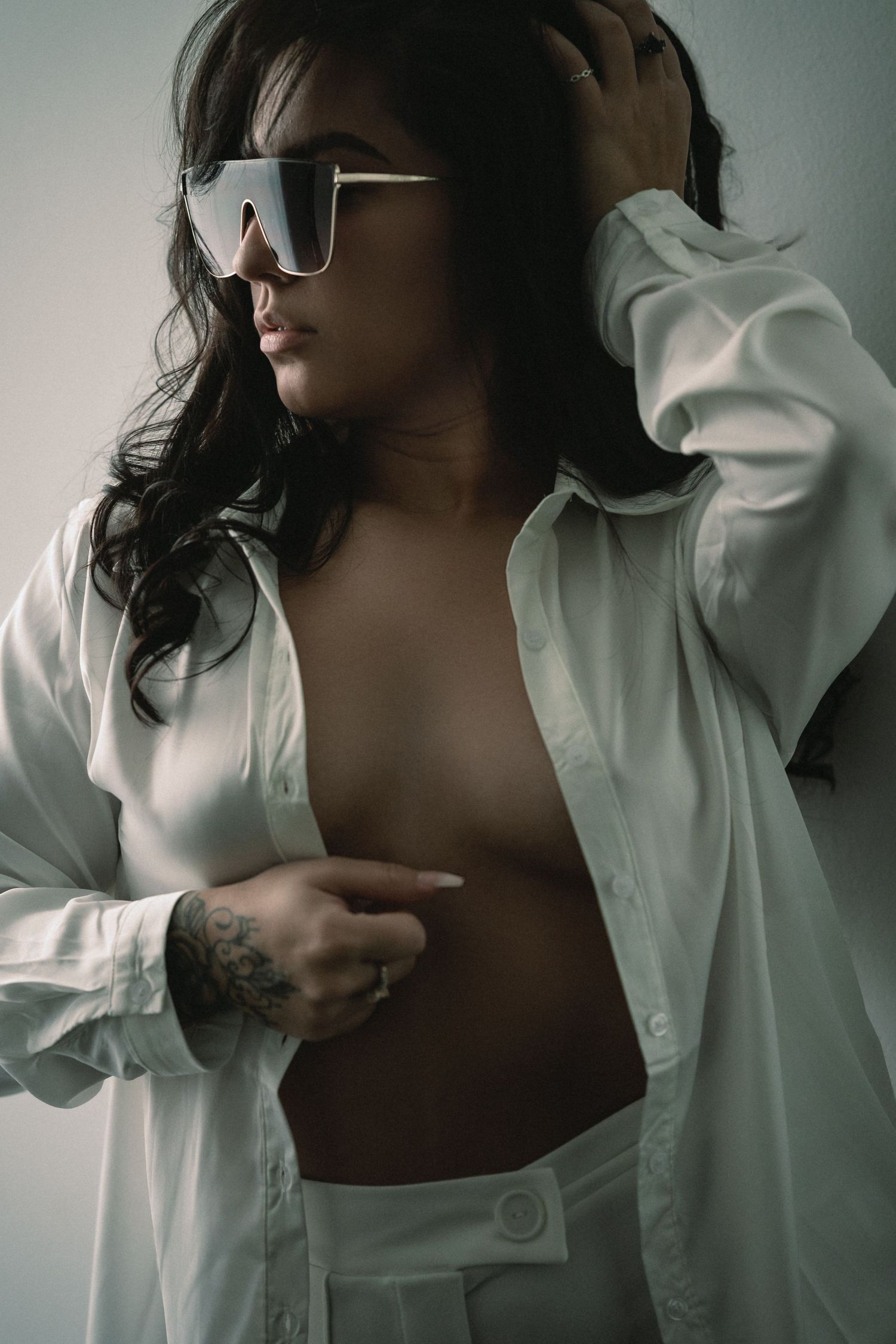 Artistic boudoir photography series showing a woman in white button down shirt against neutral background.