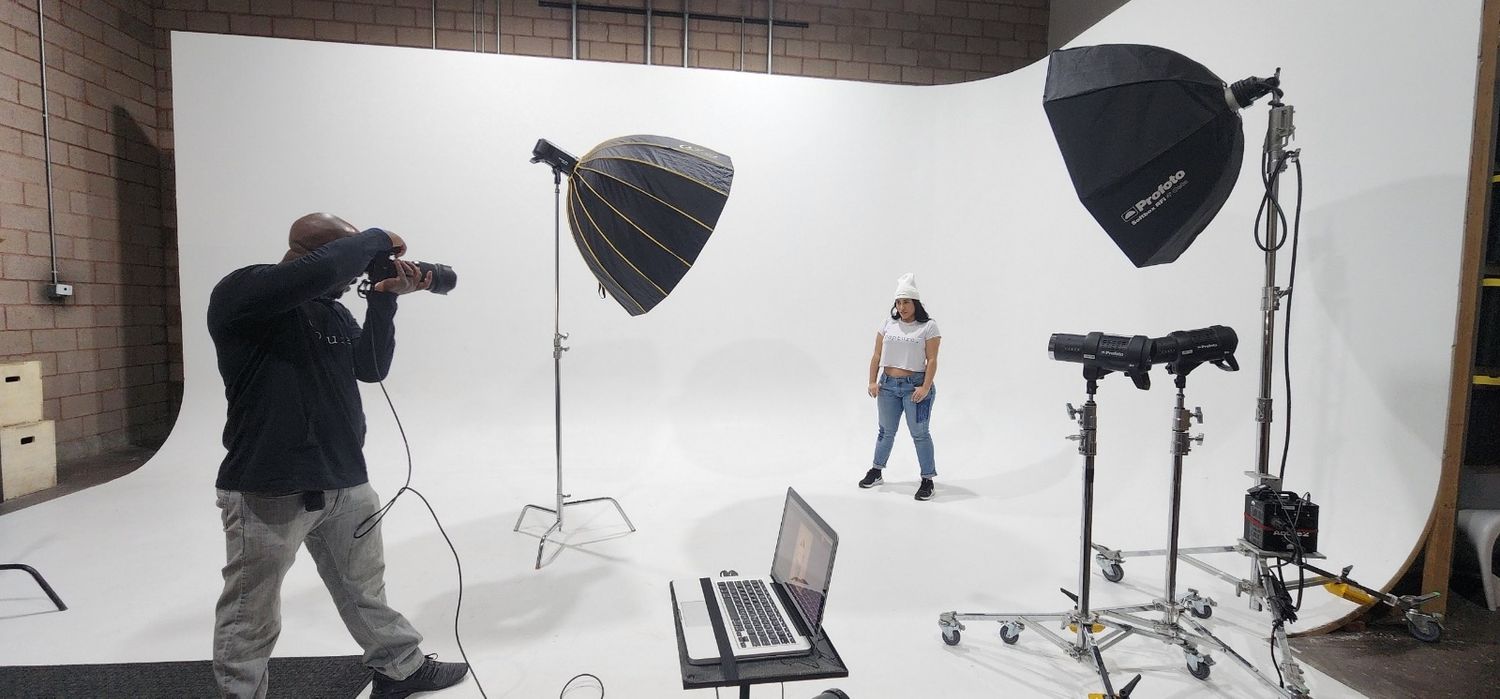 Wide panoramic view of a professional photography studio setup with lighting equipment and backdrop stands.