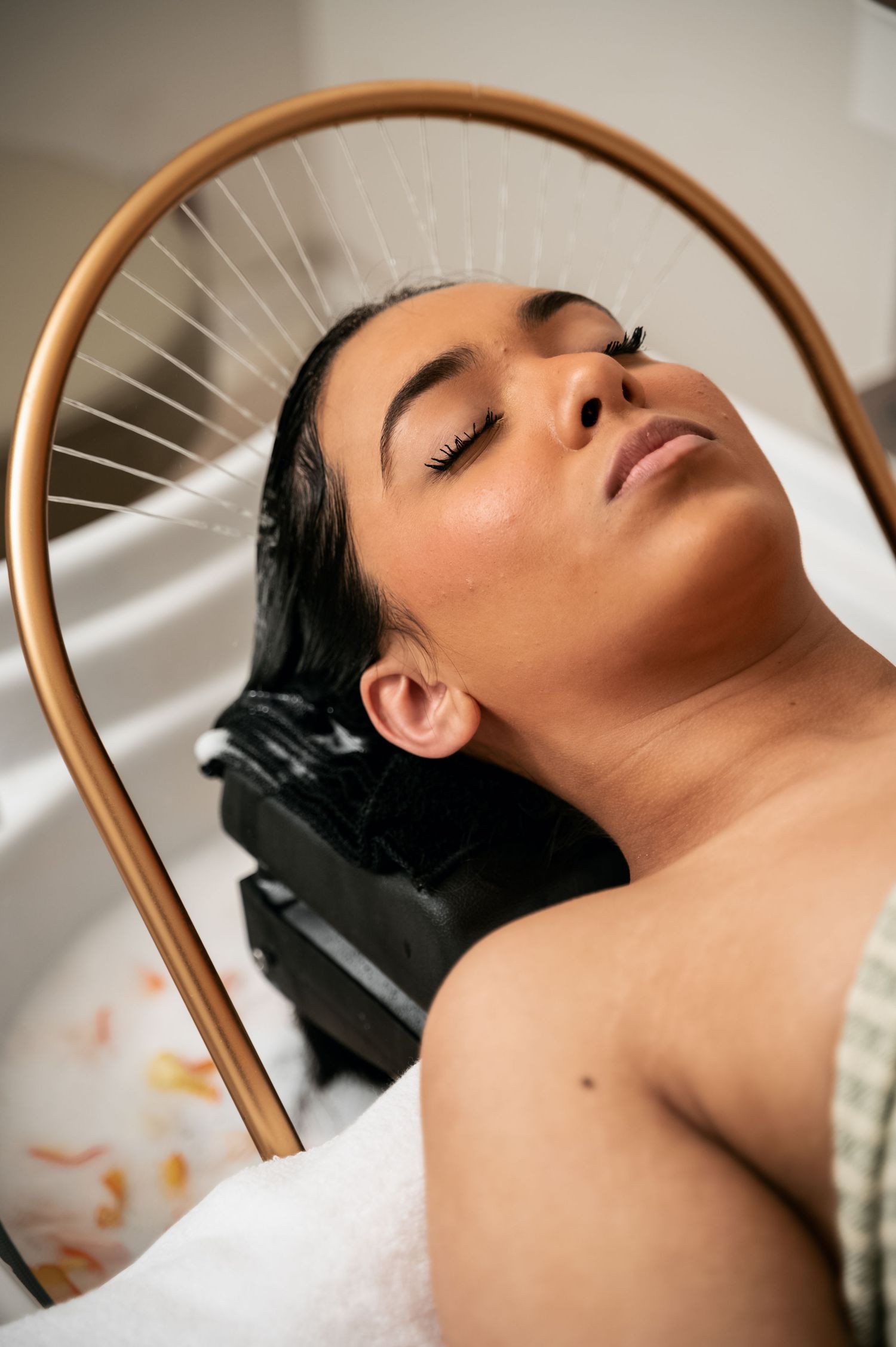 A series of close-up beauty shots showing a relaxed person with closed eyes against a copper-colored curved frame.