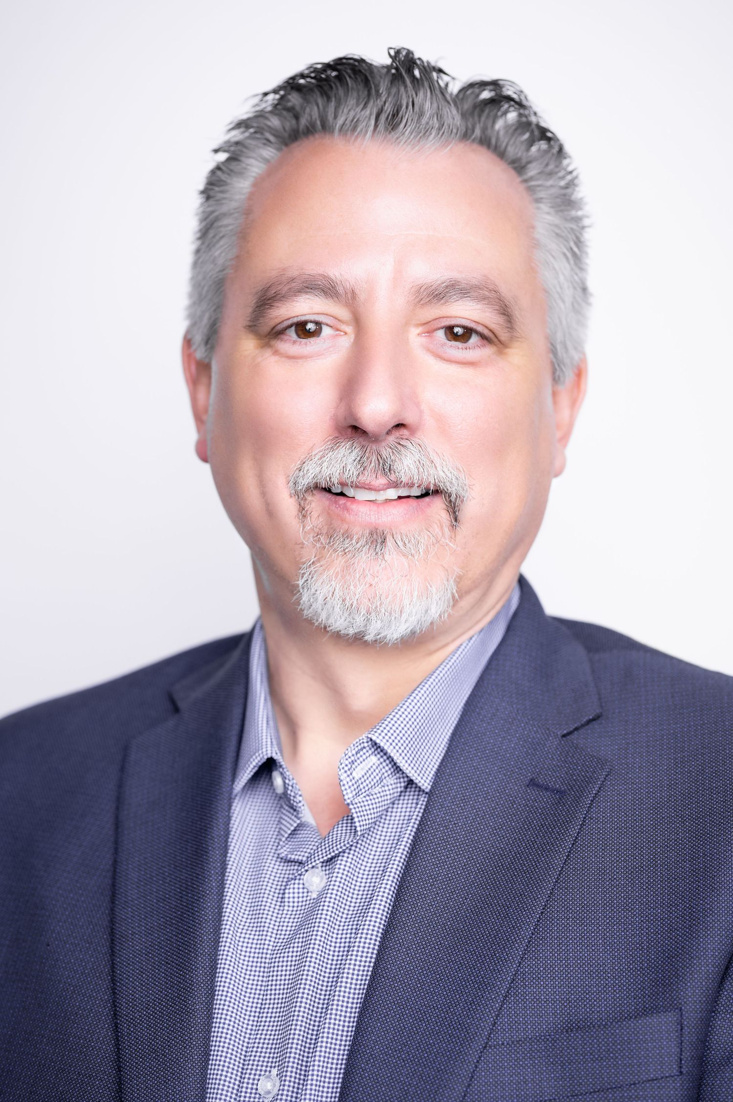 Professional headshot of a middle-aged man with salt and pepper hair and goatee wearing a navy suit jacket and gray shirt.