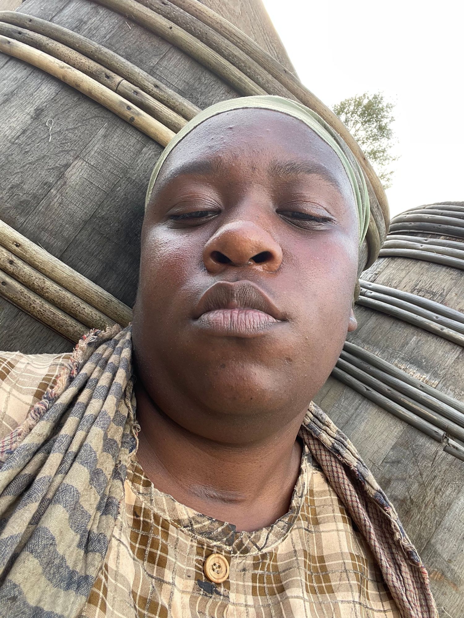 Close-up selfie showing traditional headwrap against stone architecture.