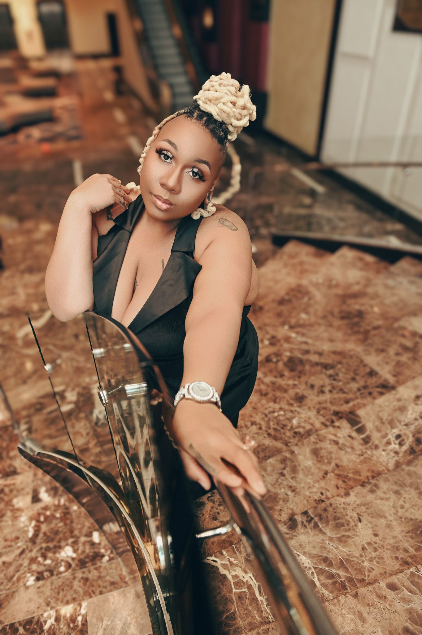 A glamorous photoshoot features a black formal dress and elegant accessories on marble flooring.