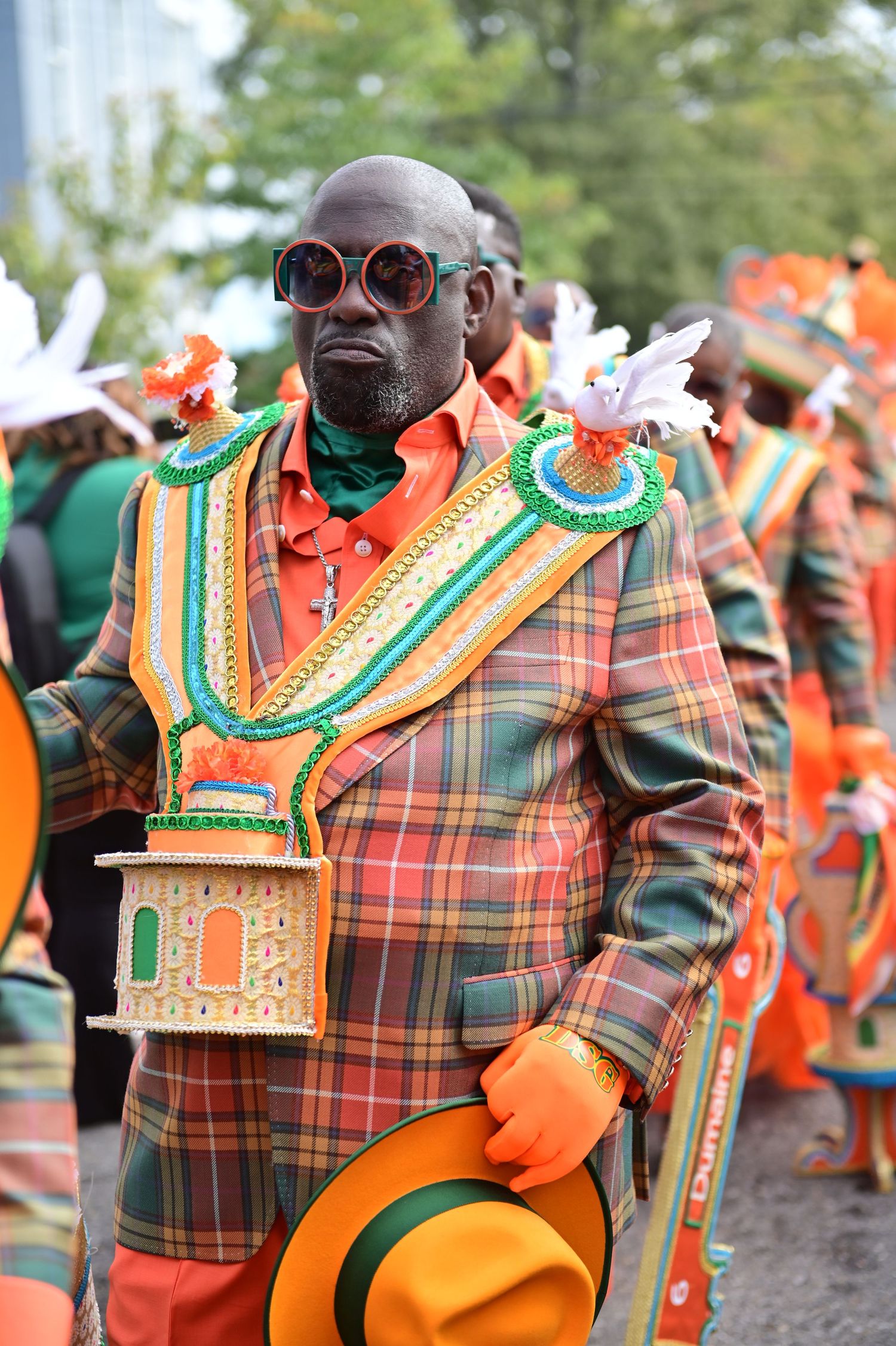 Festival performers in orange and plaid costumes with ornate decorative collars.