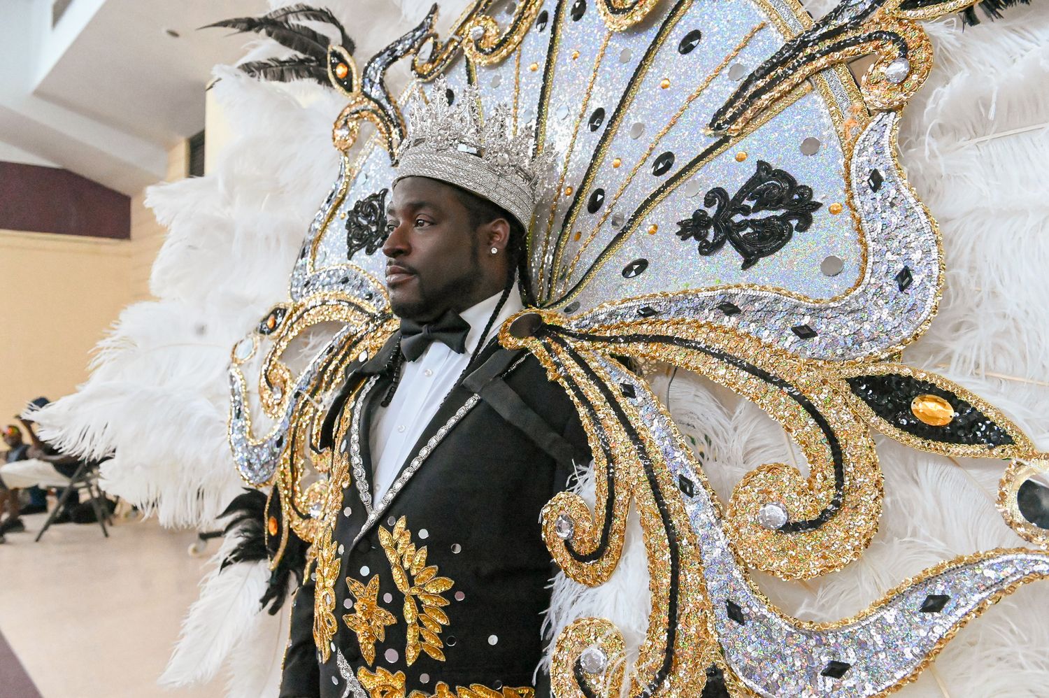 Performer wearing an elaborate black and gold butterfly-wing costume with white feathers and ornate details.