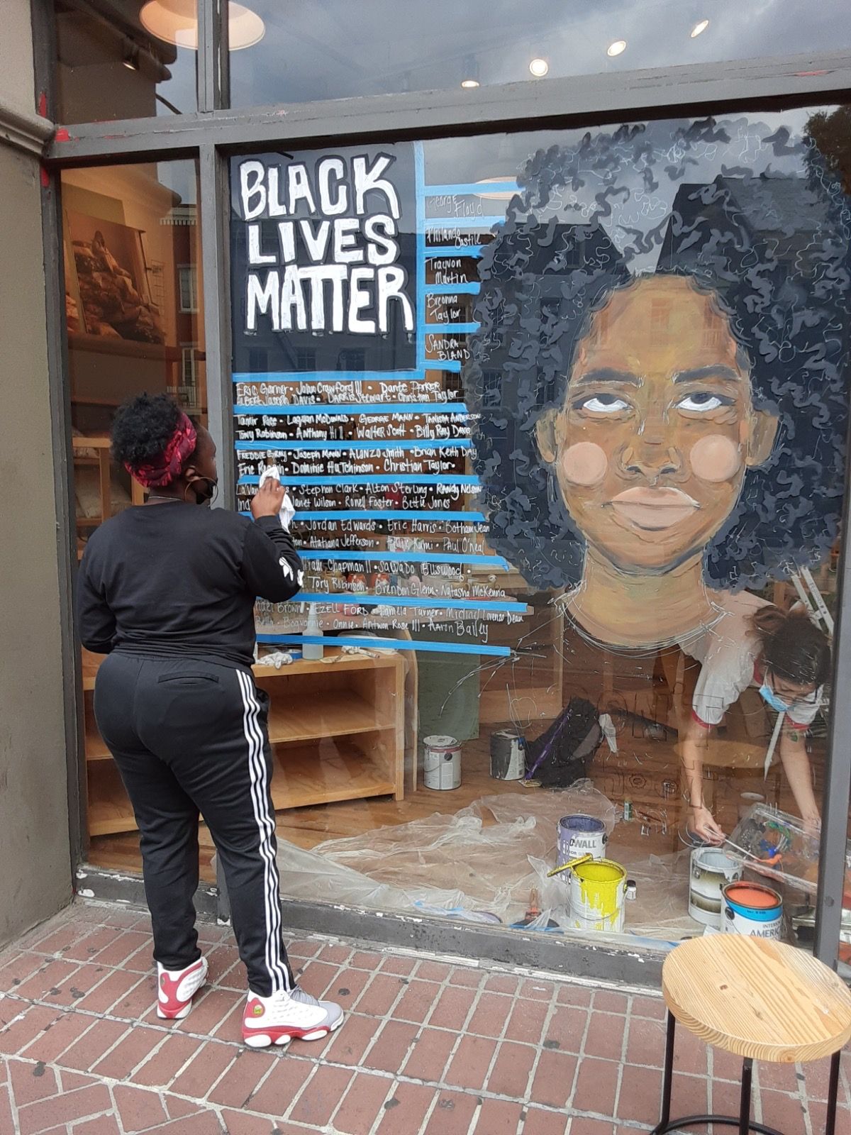 Artists creating Black Lives Matter window display at retail storefront.