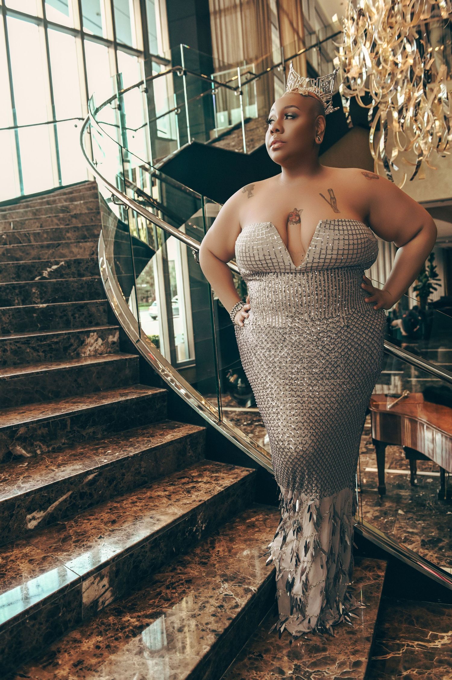 A silver beaded gown sparkles on marble stairs in an elegant setting.