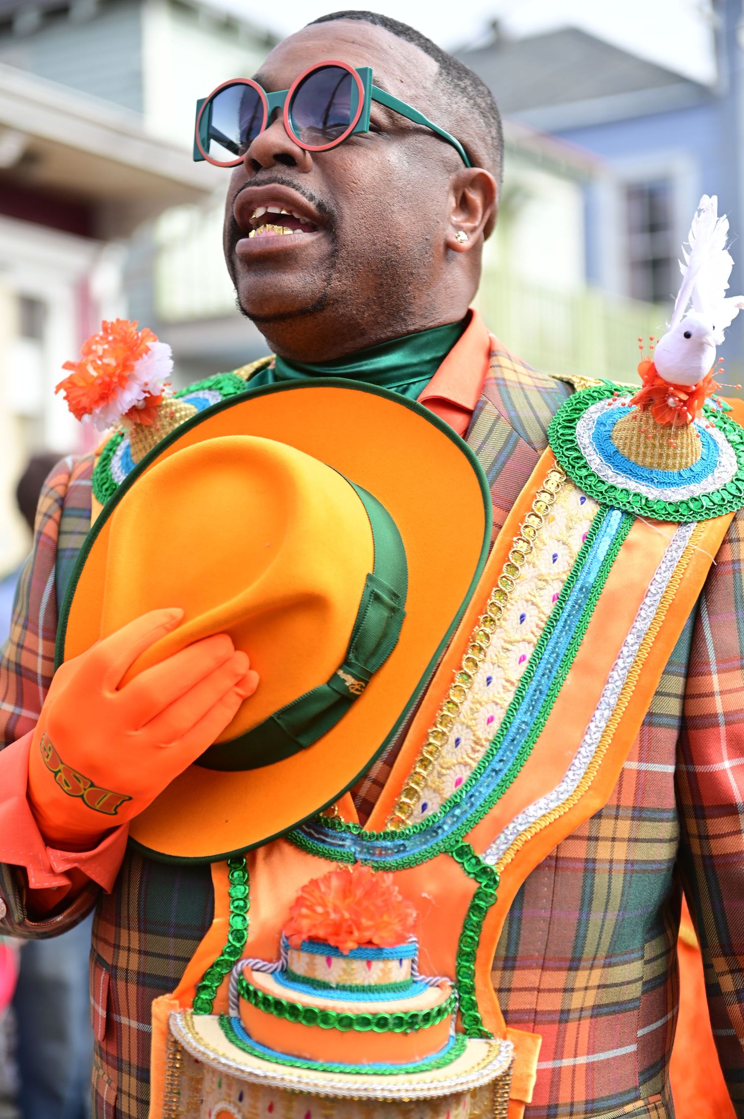 Festival participants wearing orange and plaid outfits with ornate decorative collars and sunglasses.