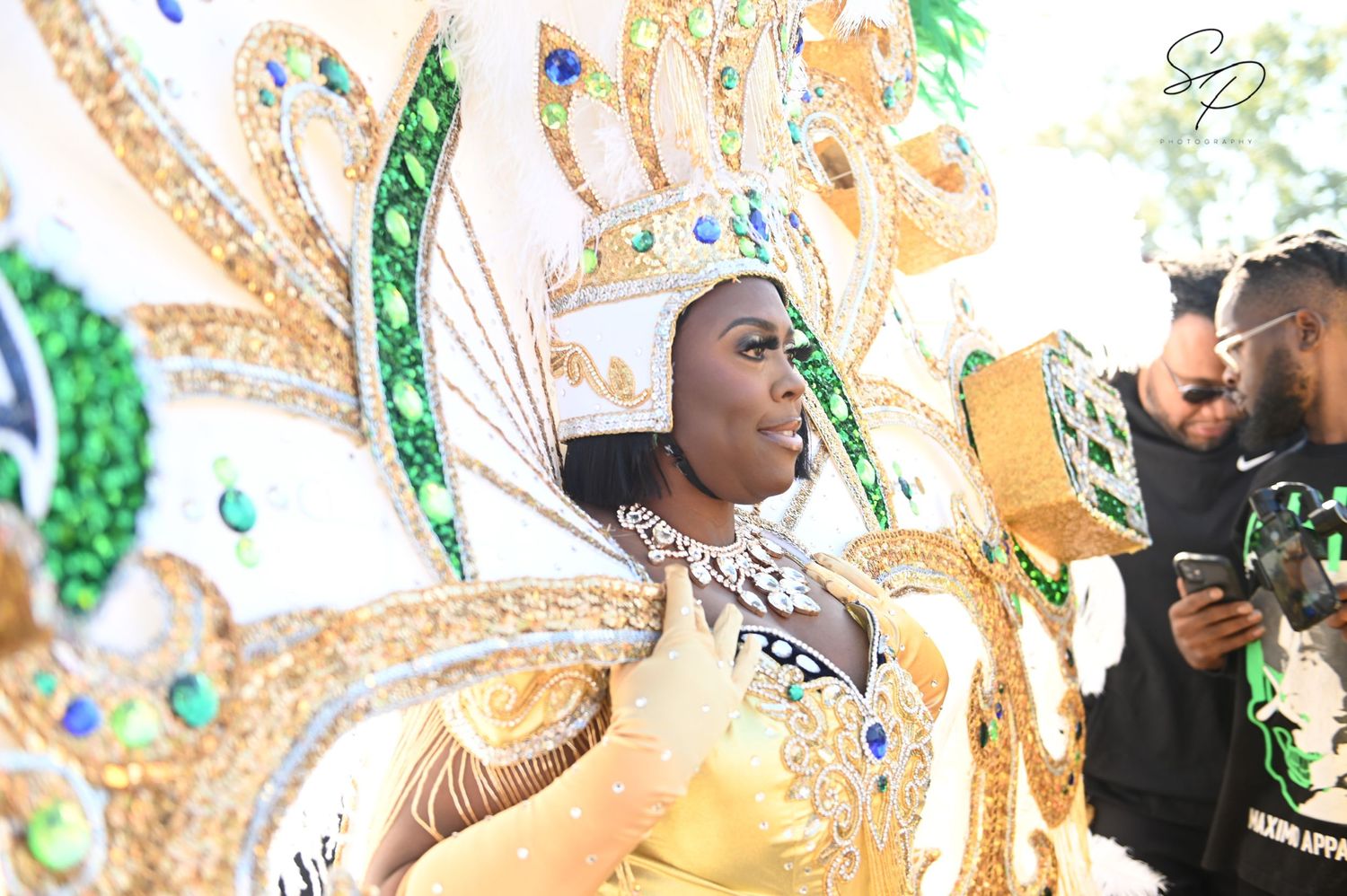 Parade performers with elaborate gold and feathered costumes dancing in formation.