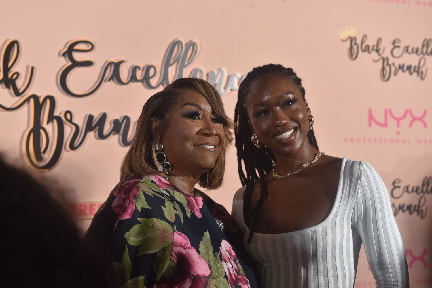 Two women smiling together at a Black Excellence Brunch event with NYX Professional Makeup branding in background.