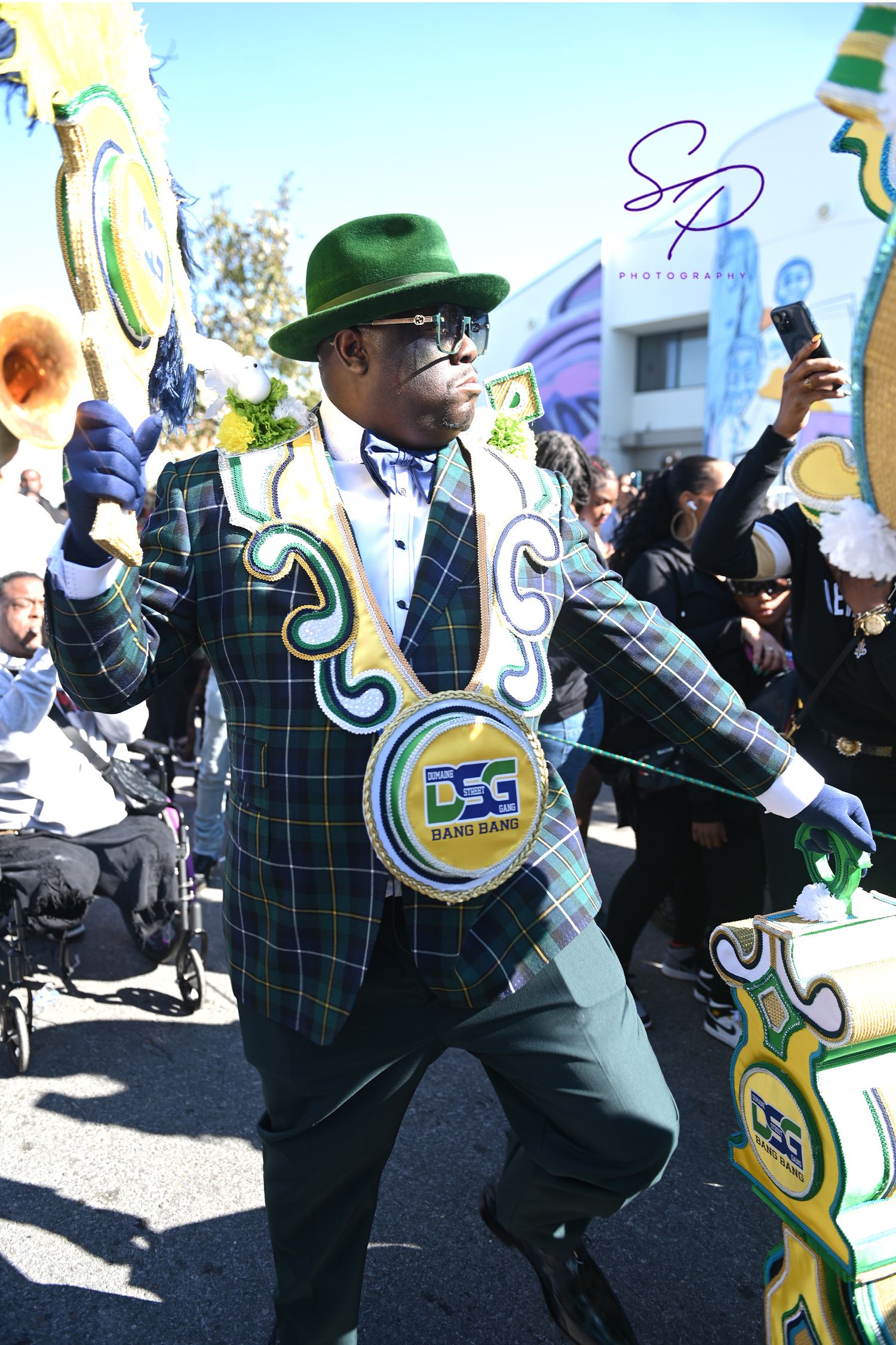 Street performers in green and yellow costumes dancing energetically during a parade.