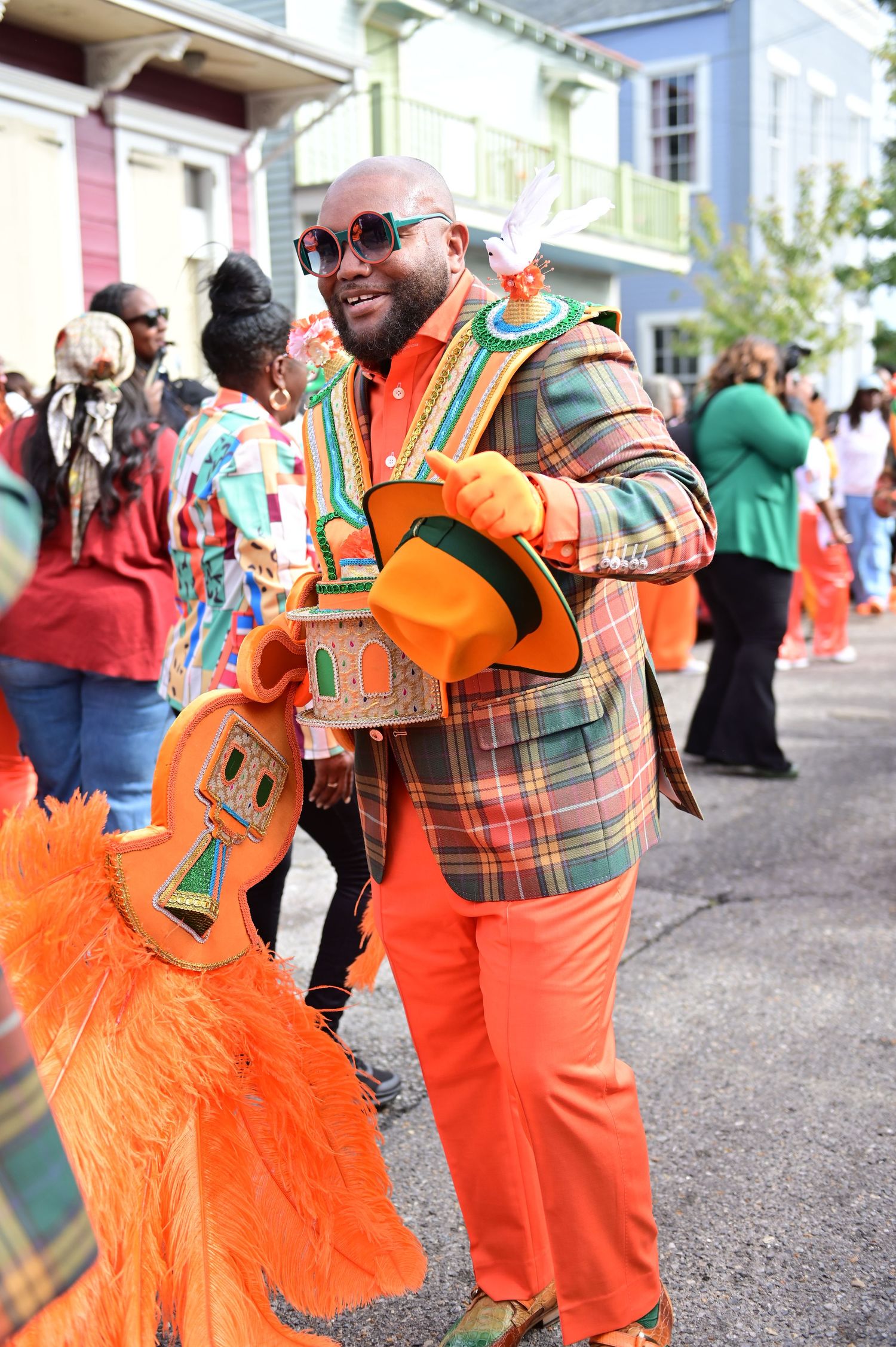 Parade participants wearing vibrant orange outfits with plaid jackets and decorative accessories.