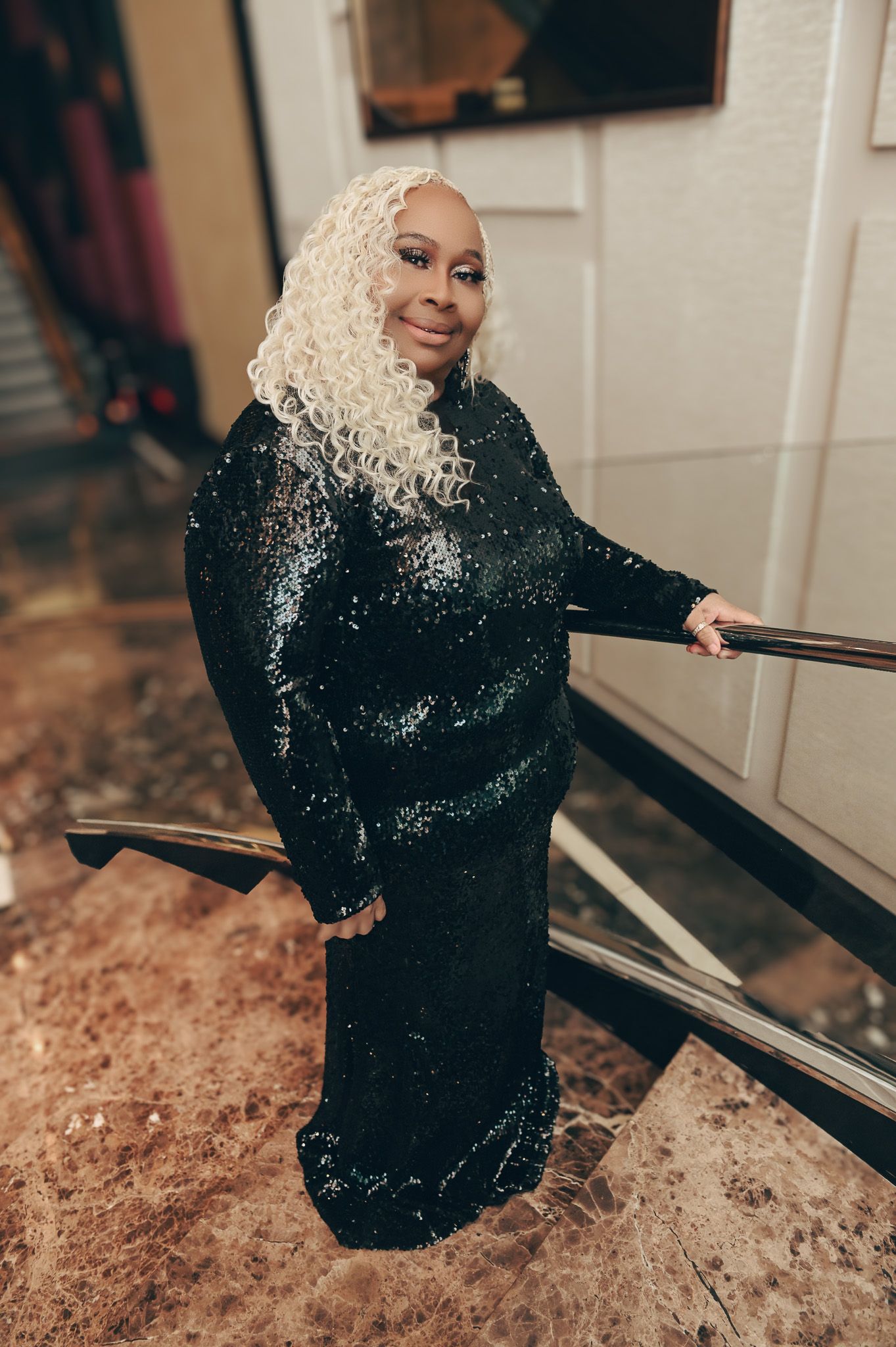 A fashion photoshoot featuring someone in a sparkly black dress on a marble surface.