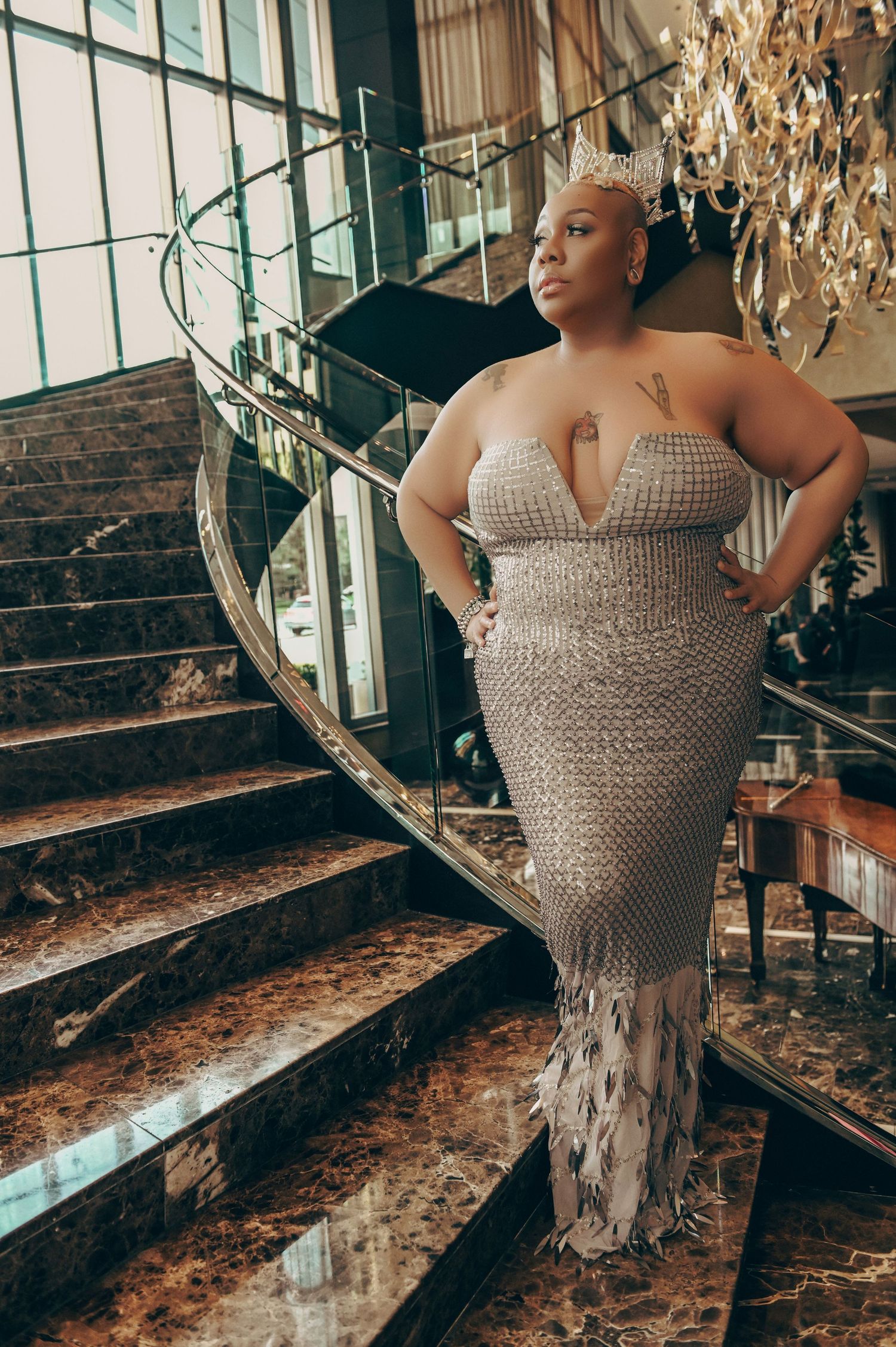 A glamour photoshoot on marble stairs featuring someone in a sparkly silver dress.