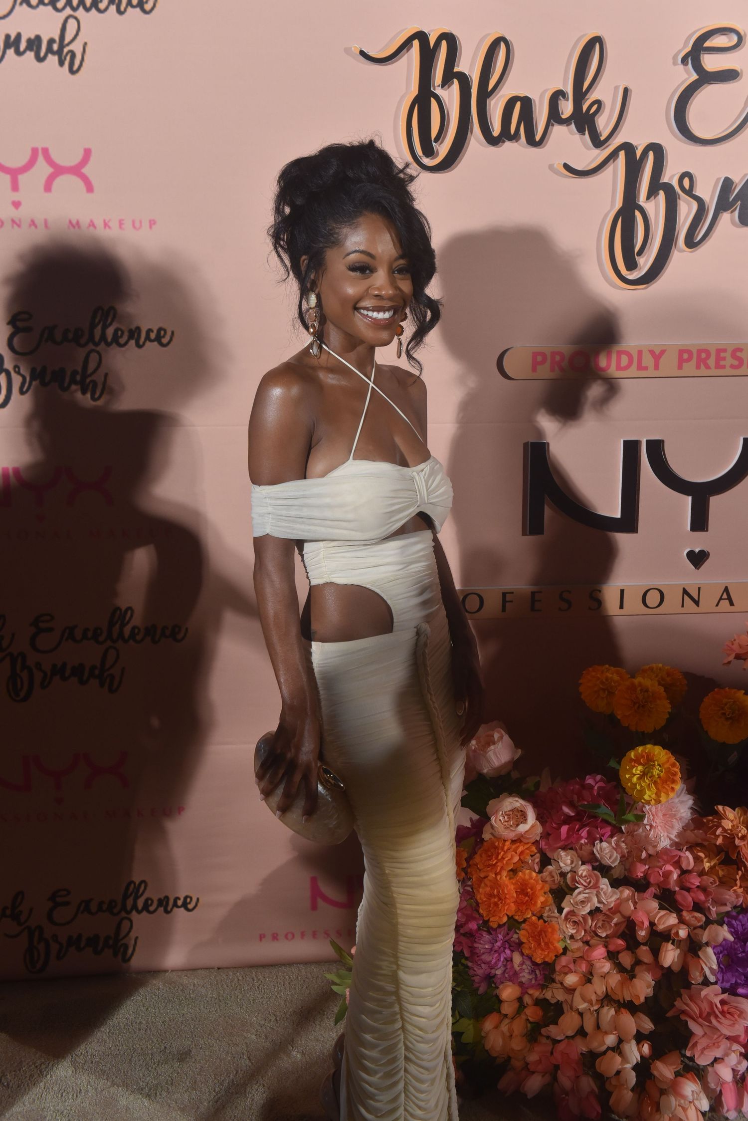 Woman in white cutout dress poses at Black Excellence Brunch event sponsored by NYX Professional Makeup.