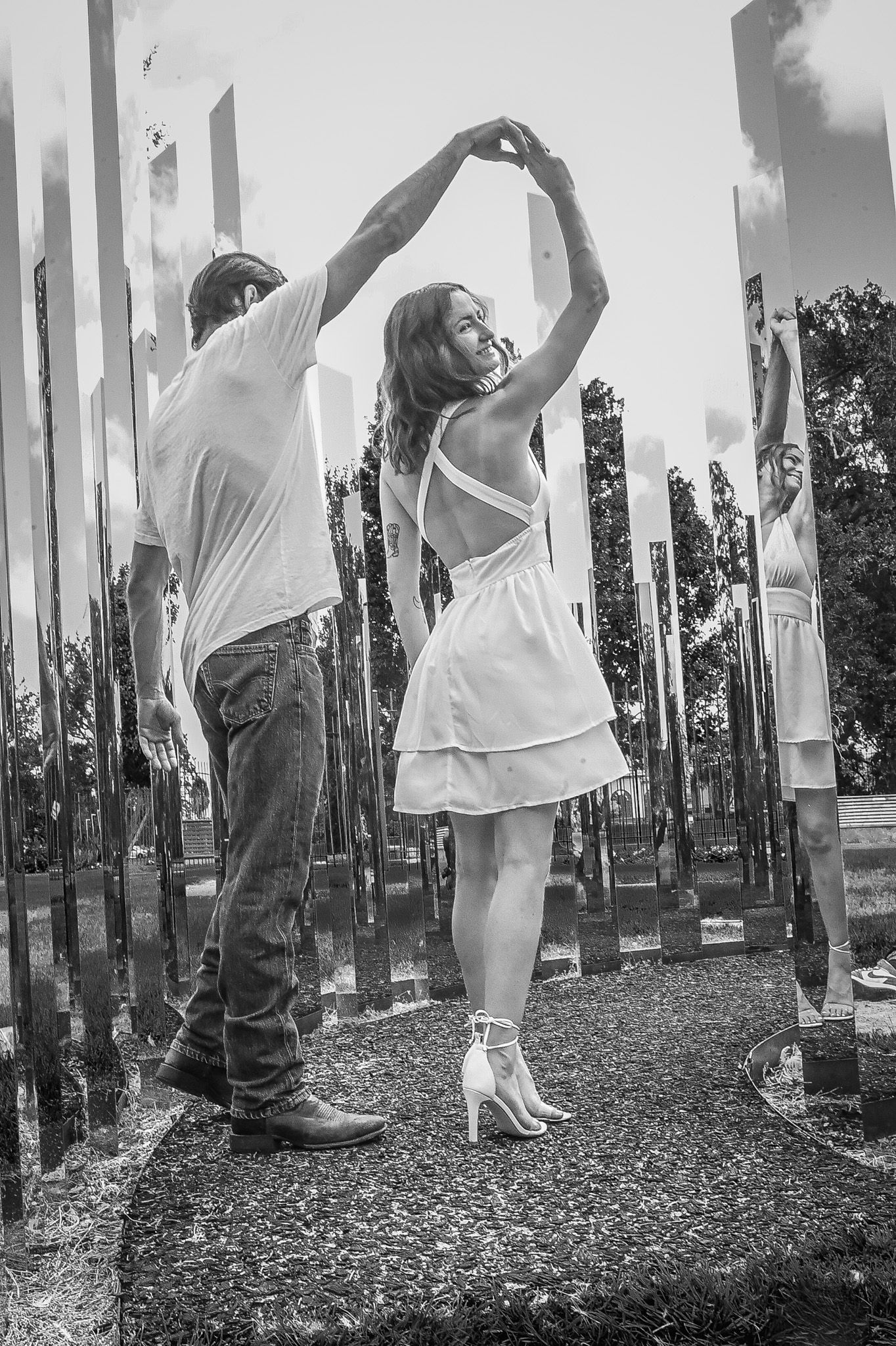 Artistic black and white photo series with people posing between reflective pillars.